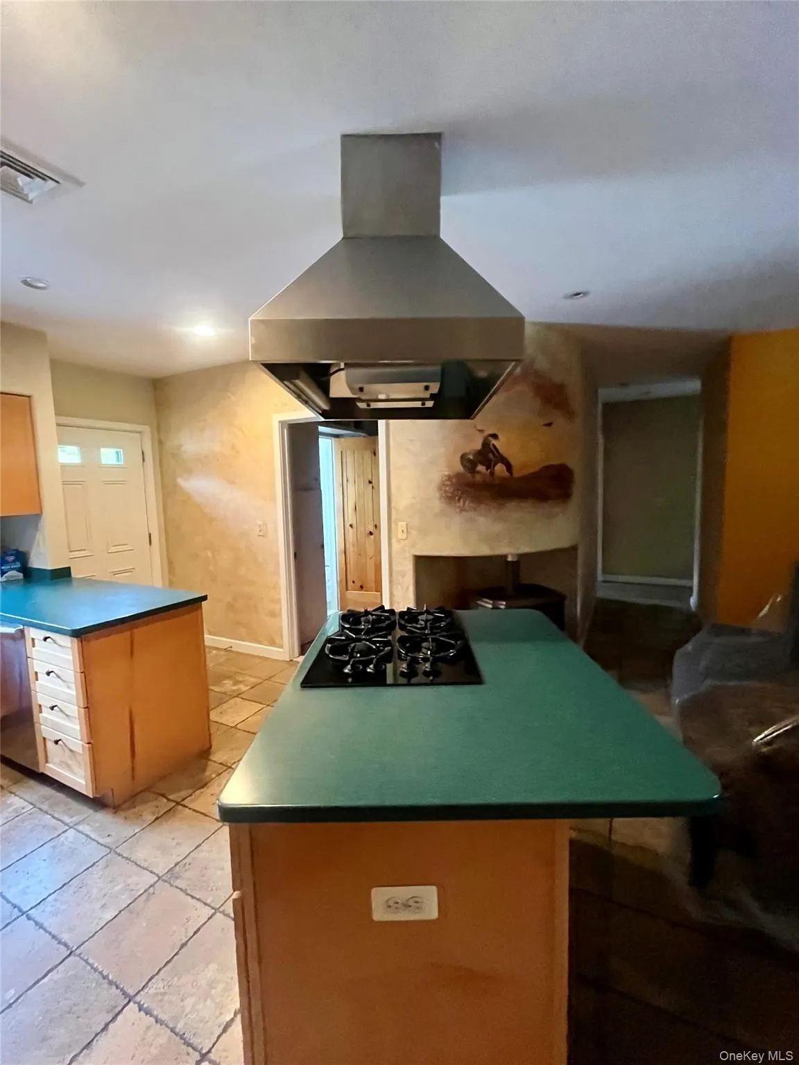 Kitchen featuring island exhaust hood, black gas stovetop, a center island, a peninsula, and dark countertops Kitchen featuring island exhaust hood, black gas stovetop, a center island, a peninsula, and dark countertops