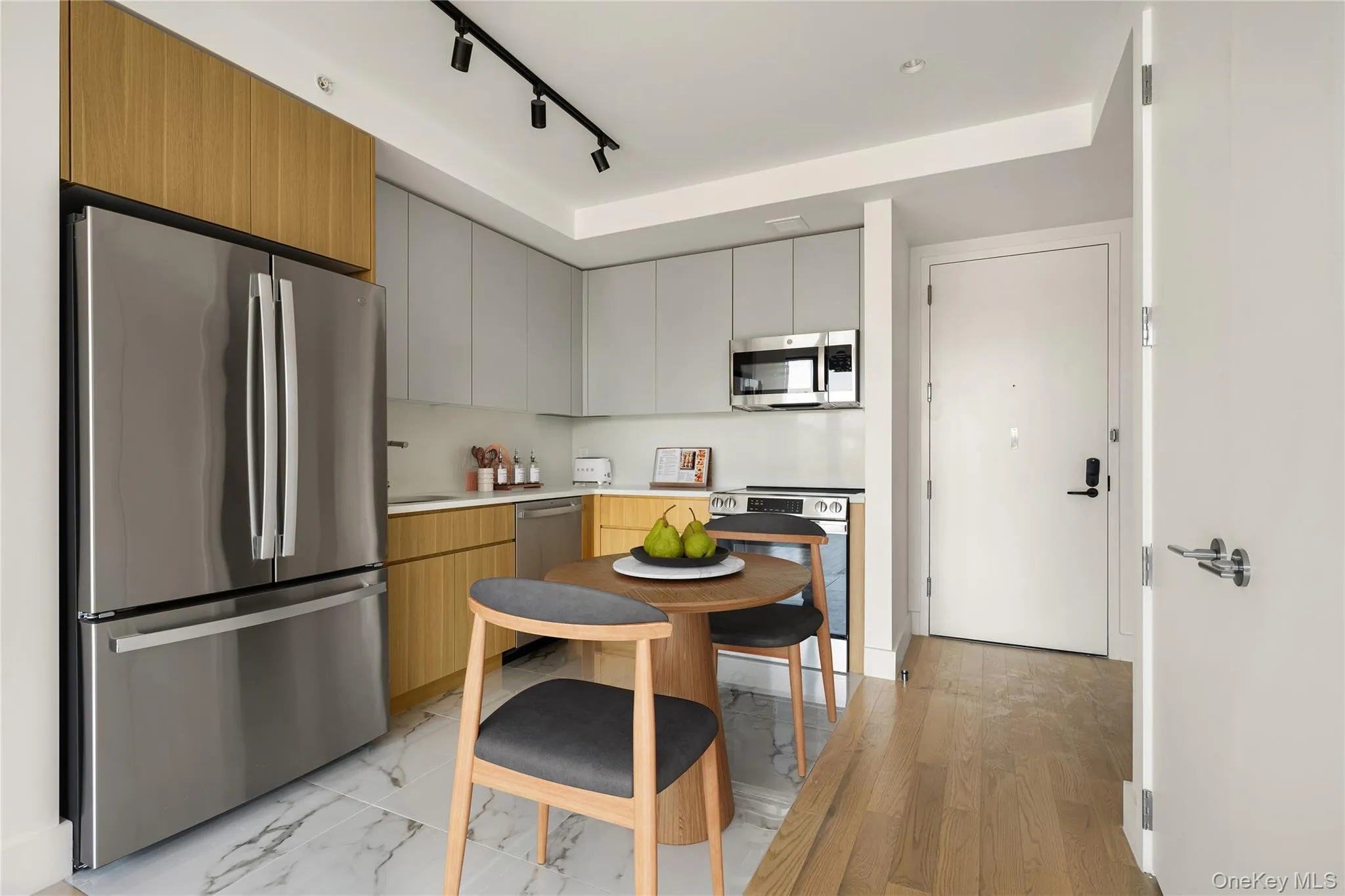 Kitchen featuring stainless steel appliances, light countertops, gray cabinets, modern cabinets, and track lighting Kitchen featuring stainless steel appliances, light countertops, gray cabinets, modern cabinets, and track lighting