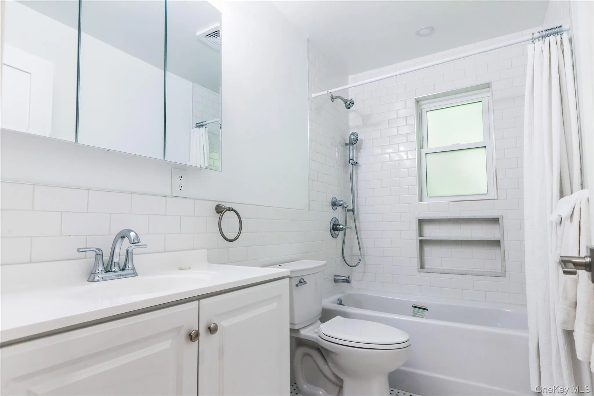 Bathroom featuring shower / tub combo with curtain, vanity, tile walls, and decorative backsplash Bathroom featuring shower / tub combo with curtain, vanity, tile walls, and decorative backsplash