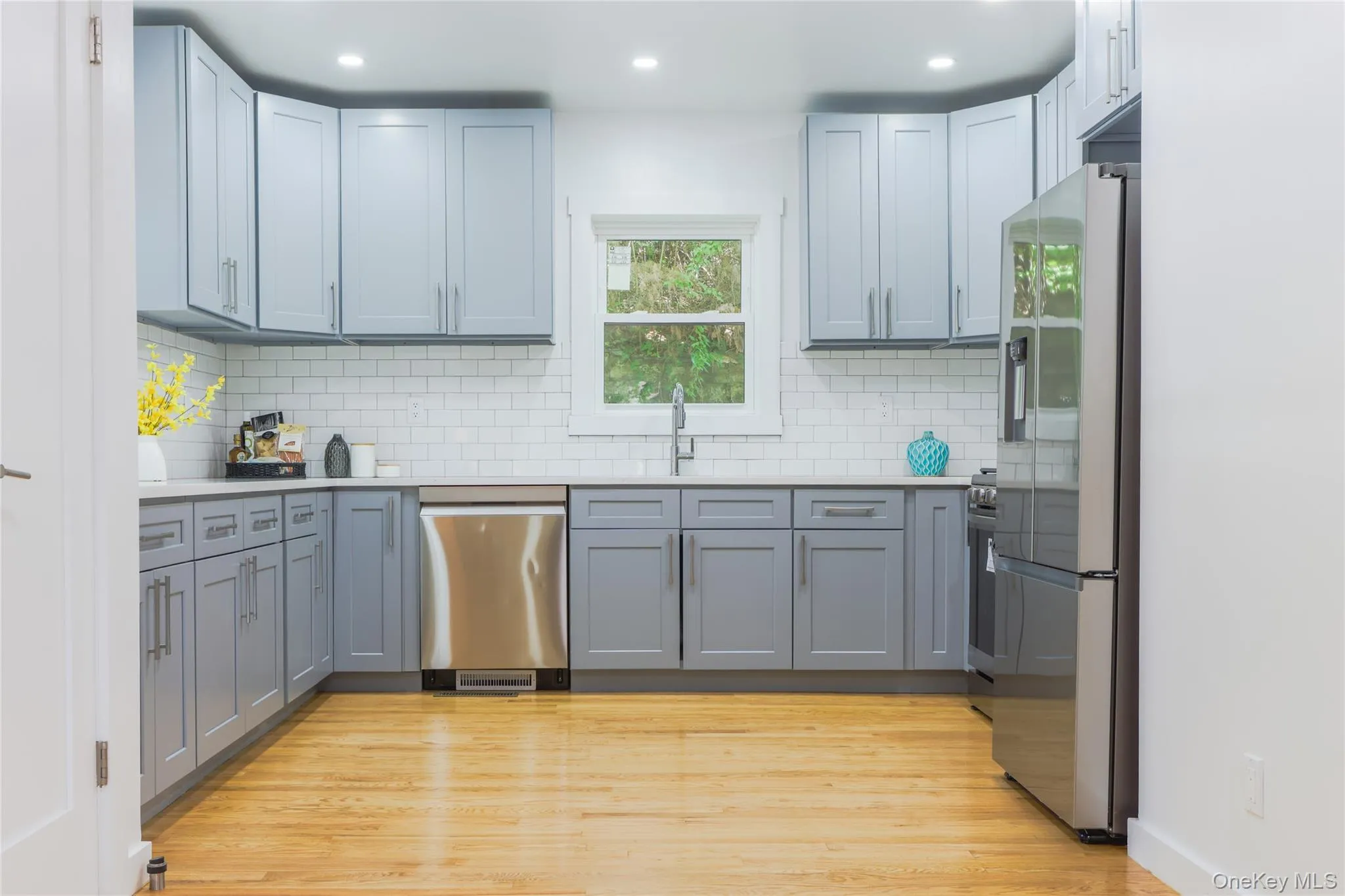 Kitchen featuring appliances with stainless steel finishes, light wood-type flooring, decorative backsplash, light stone countertops, and recessed lighting Kitchen featuring appliances with stainless steel finishes, light wood-type flooring, decorative backsplash, light stone countertops, and recessed lighting