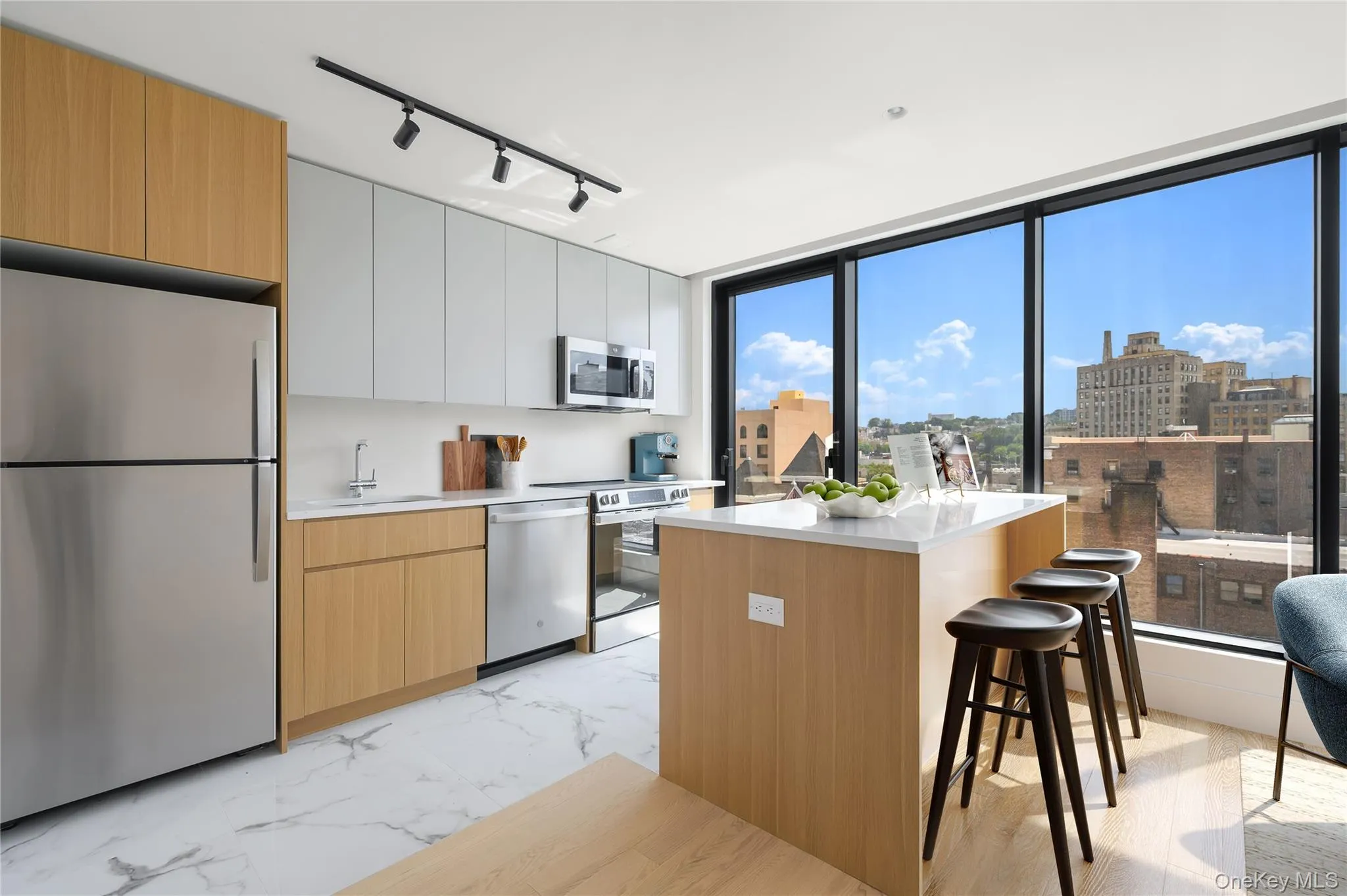 Kitchen with stainless steel appliances, a kitchen bar, white cabinets, modern cabinets, and rail lighting Kitchen with stainless steel appliances, a kitchen bar, white cabinets, modern cabinets, and rail lighting