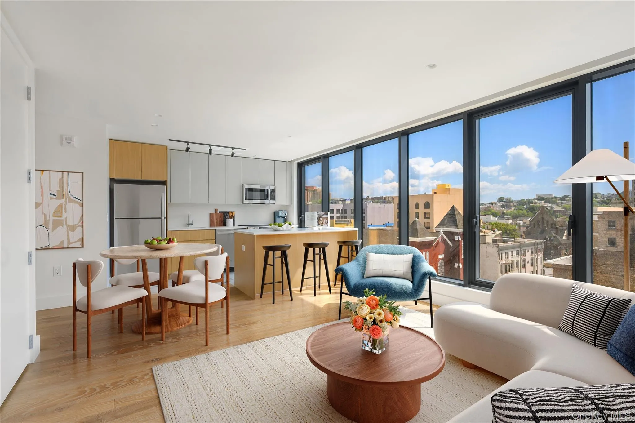 Living area with light wood-style flooring, expansive windows, and track lighting Living area with light wood-style flooring, expansive windows, and track lighting