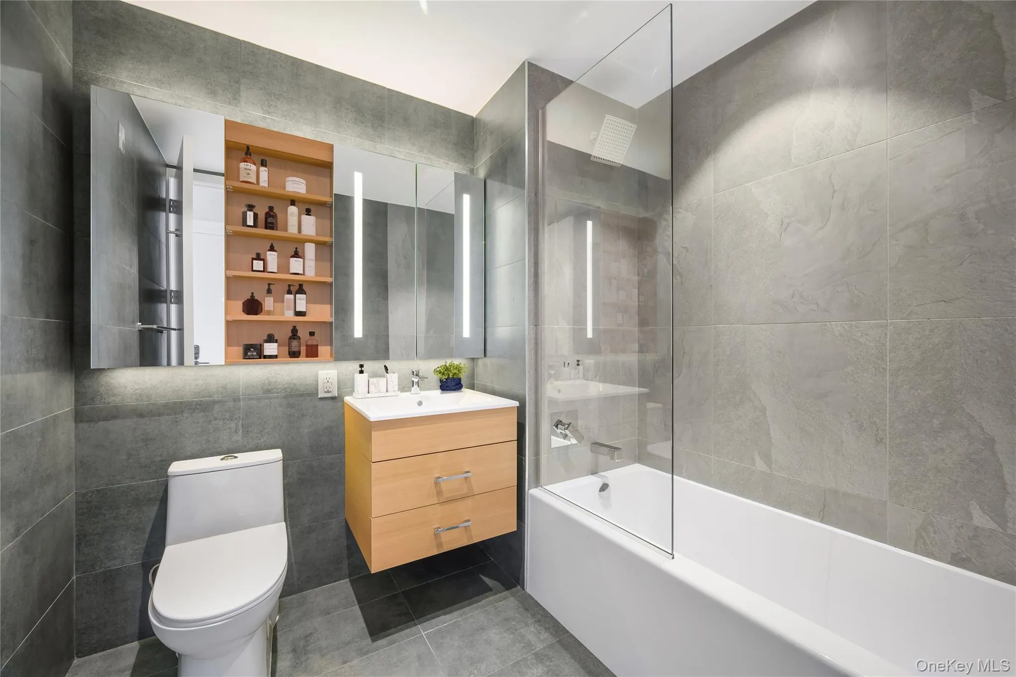 Bathroom featuring tile walls, tub / shower combination, vanity, and tile patterned flooring Bathroom featuring tile walls, tub / shower combination, vanity, and tile patterned flooring