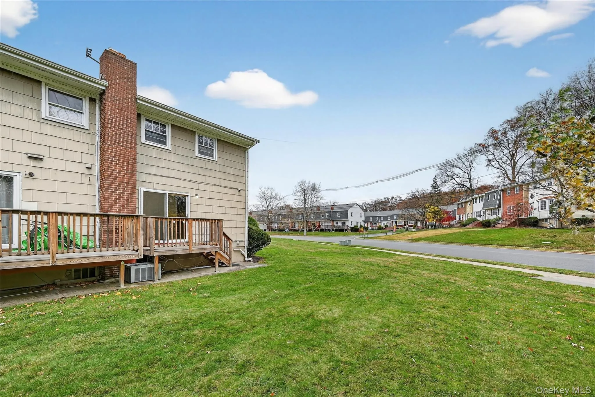 View of green lawn featuring a wooden deck and a residential view View of green lawn featuring a wooden deck and a residential view