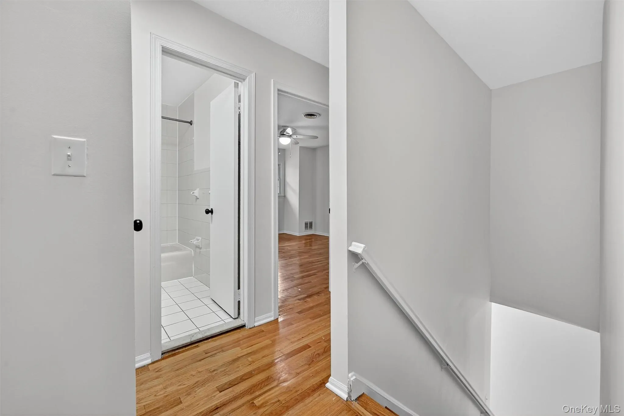 Hall with an upstairs landing and light wood finished floors Hall with an upstairs landing and light wood finished floors