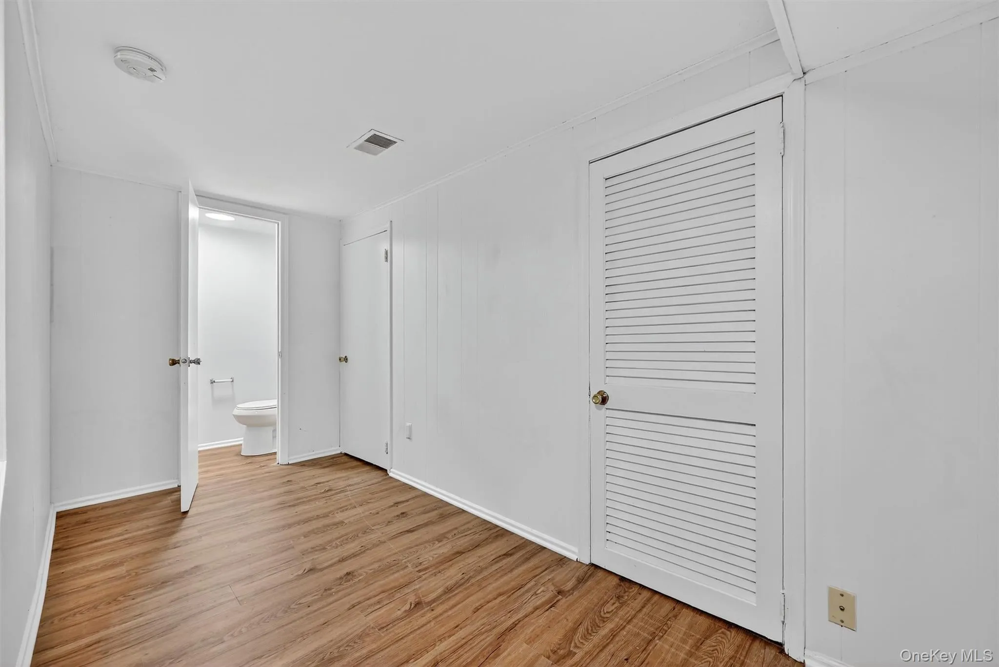 Unfurnished bedroom with light wood finished floors and connected bathroom Unfurnished bedroom with light wood finished floors and connected bathroom