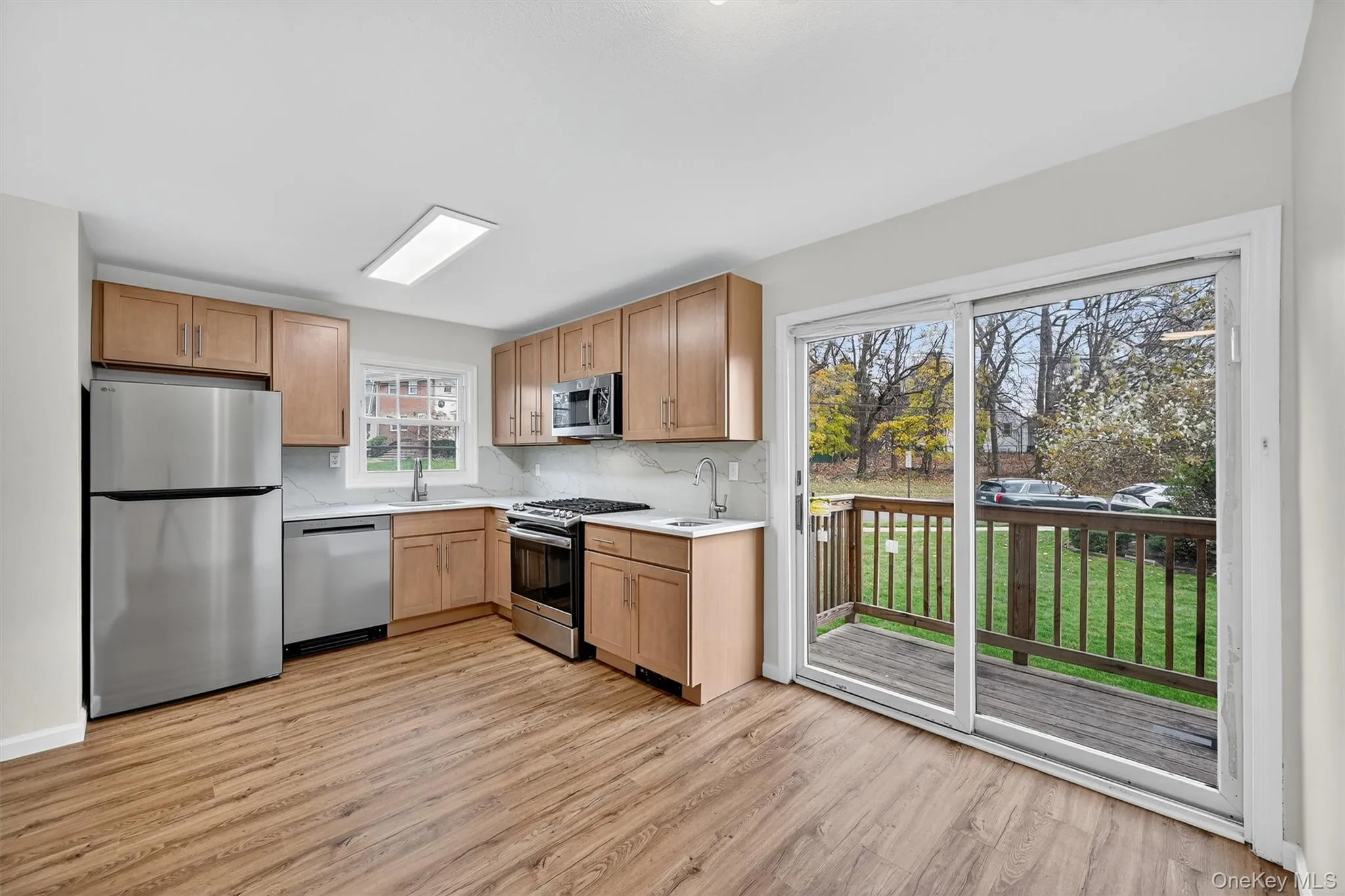 Kitchen with appliances with stainless steel finishes, light wood-style floors, tasteful backsplash, and light brown cabinetry Kitchen with appliances with stainless steel finishes, light wood-style floors, tasteful backsplash, and light brown cabinetry