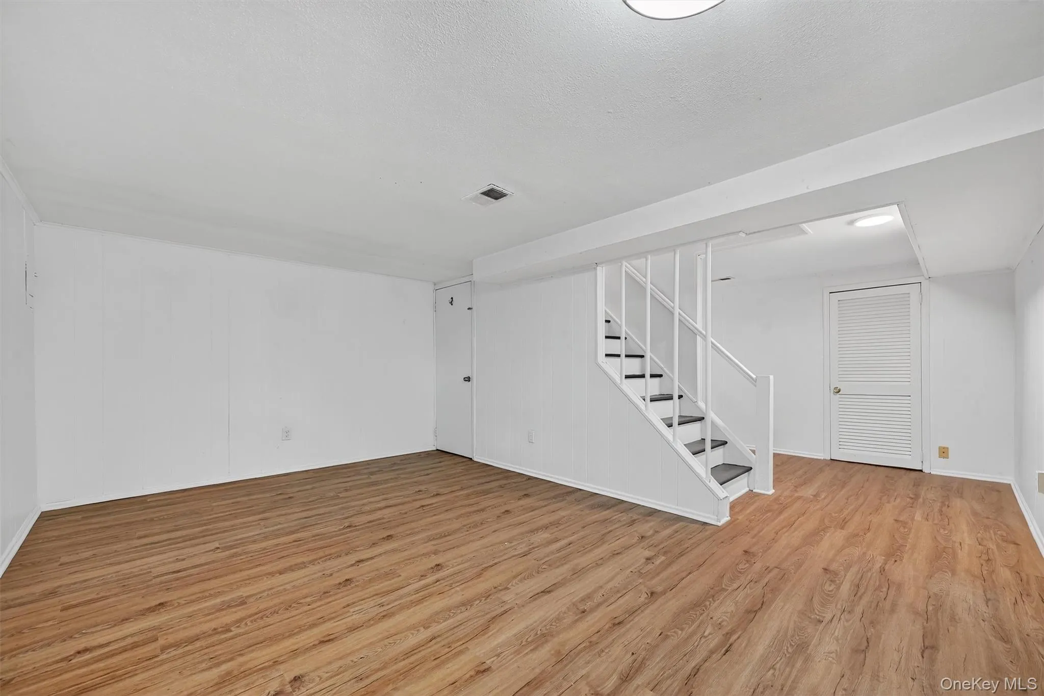 Finished below grade area featuring light wood-style floors and stairway Finished below grade area featuring light wood-style floors and stairway