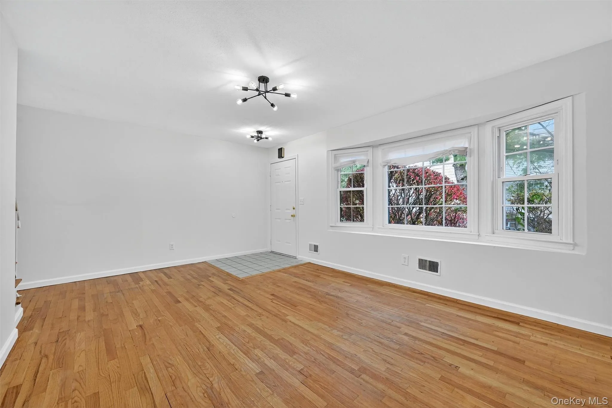 Unfurnished room with light wood finished floors and a chandelier Unfurnished room with light wood finished floors and a chandelier