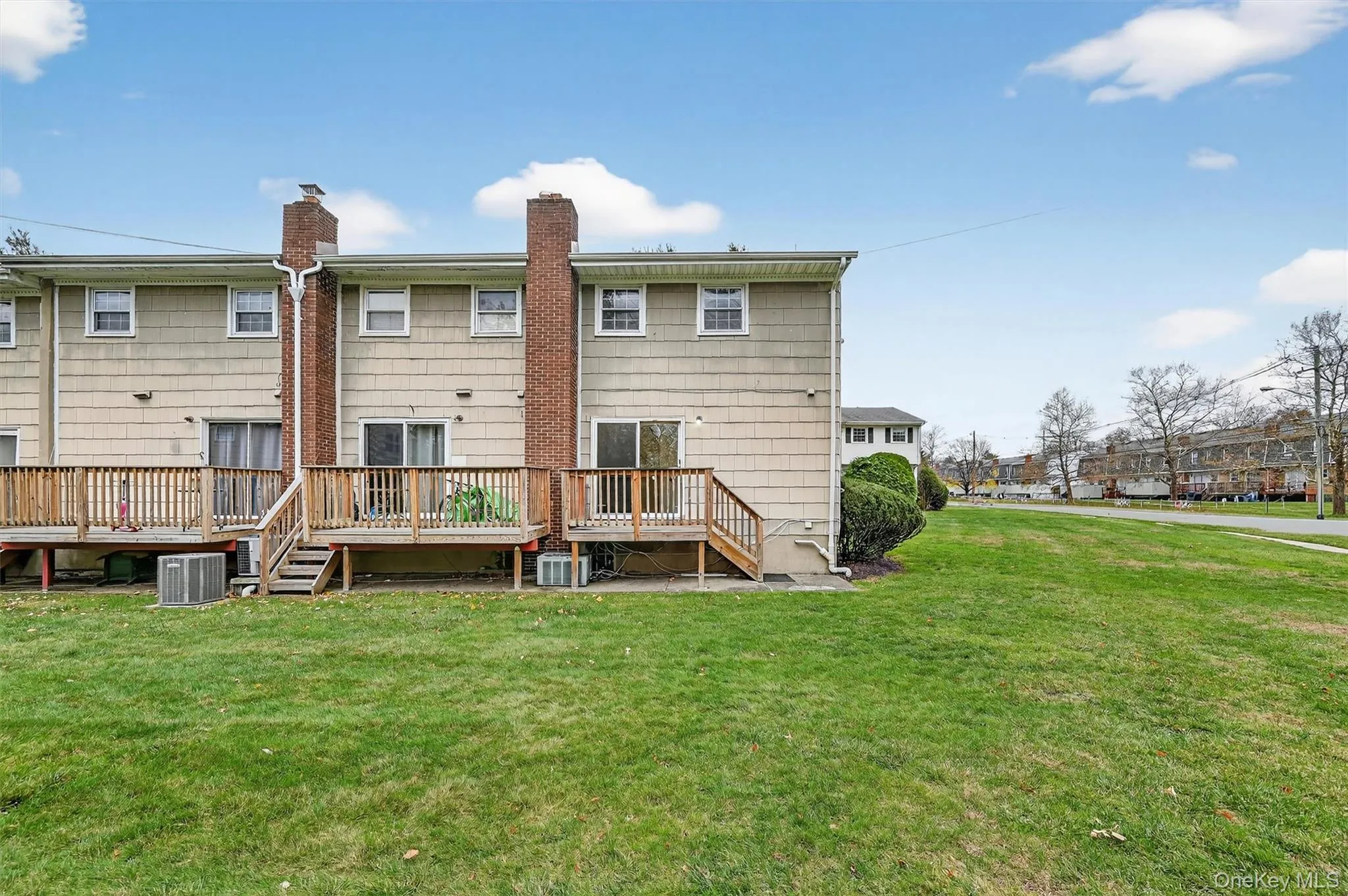 Rear view of property with a chimney, a deck, and a yard Rear view of property with a chimney, a deck, and a yard