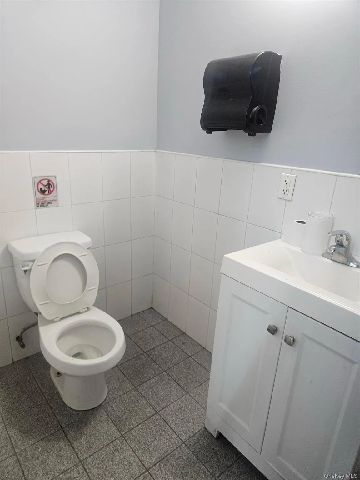Half bath featuring vanity, tile walls, and a wainscoted wall Half bath featuring vanity, tile walls, and a wainscoted wall