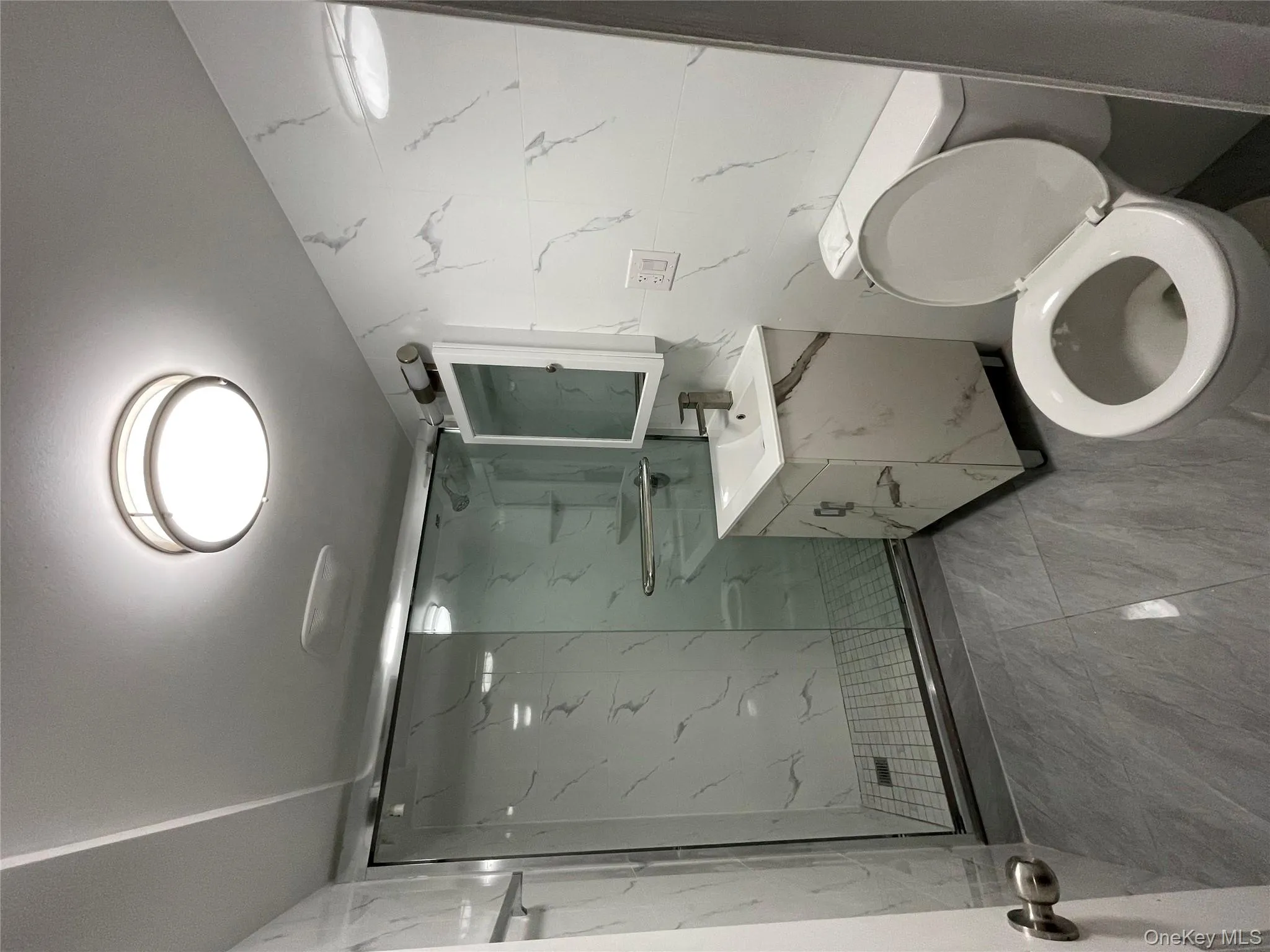 Bathroom with a marble finish shower, vanity, and tile walls Bathroom with a marble finish shower, vanity, and tile walls