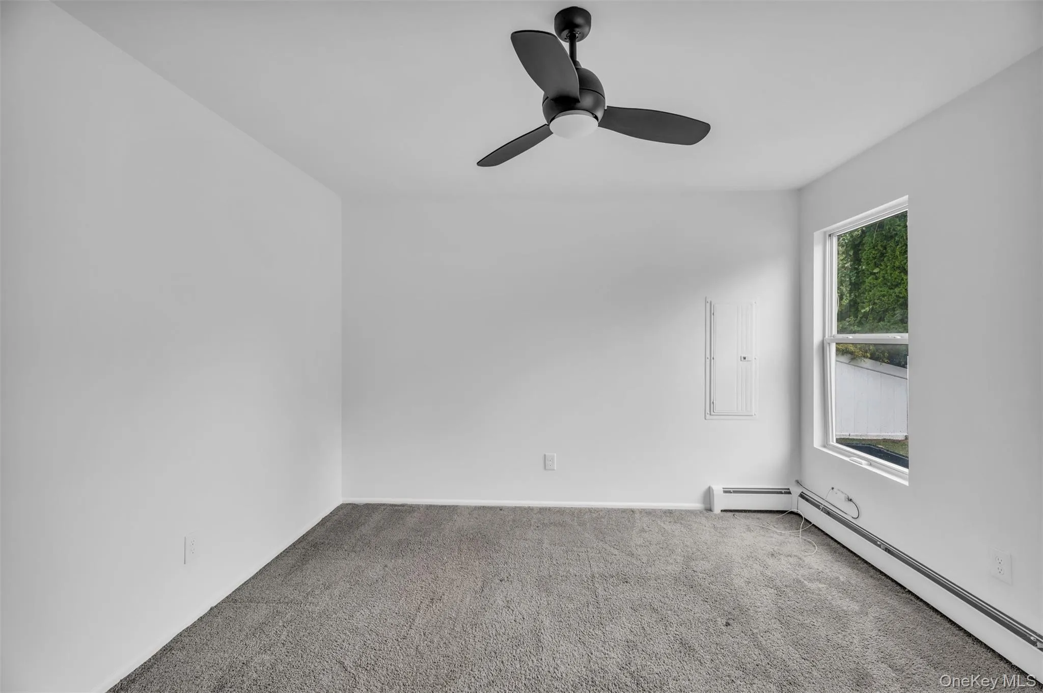 Carpeted spare room with baseboard heating and a ceiling fan Carpeted spare room with baseboard heating and a ceiling fan