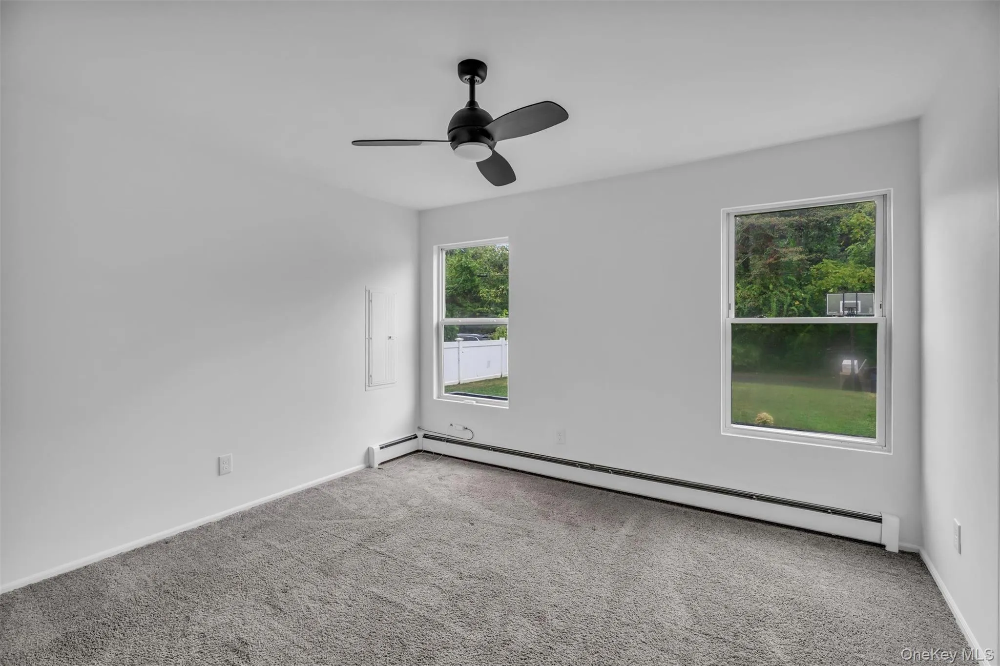 Empty room with a baseboard radiator, carpet, and a ceiling fan Empty room with a baseboard radiator, carpet, and a ceiling fan