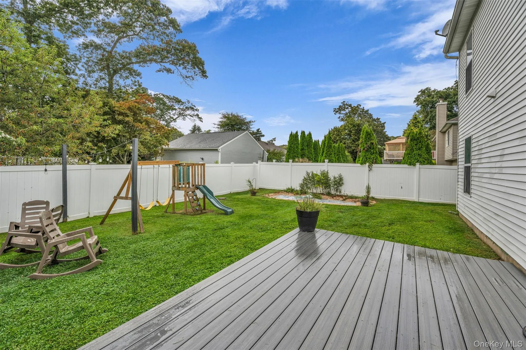 Wooden deck with a playground and a fenced backyard Wooden deck with a playground and a fenced backyard