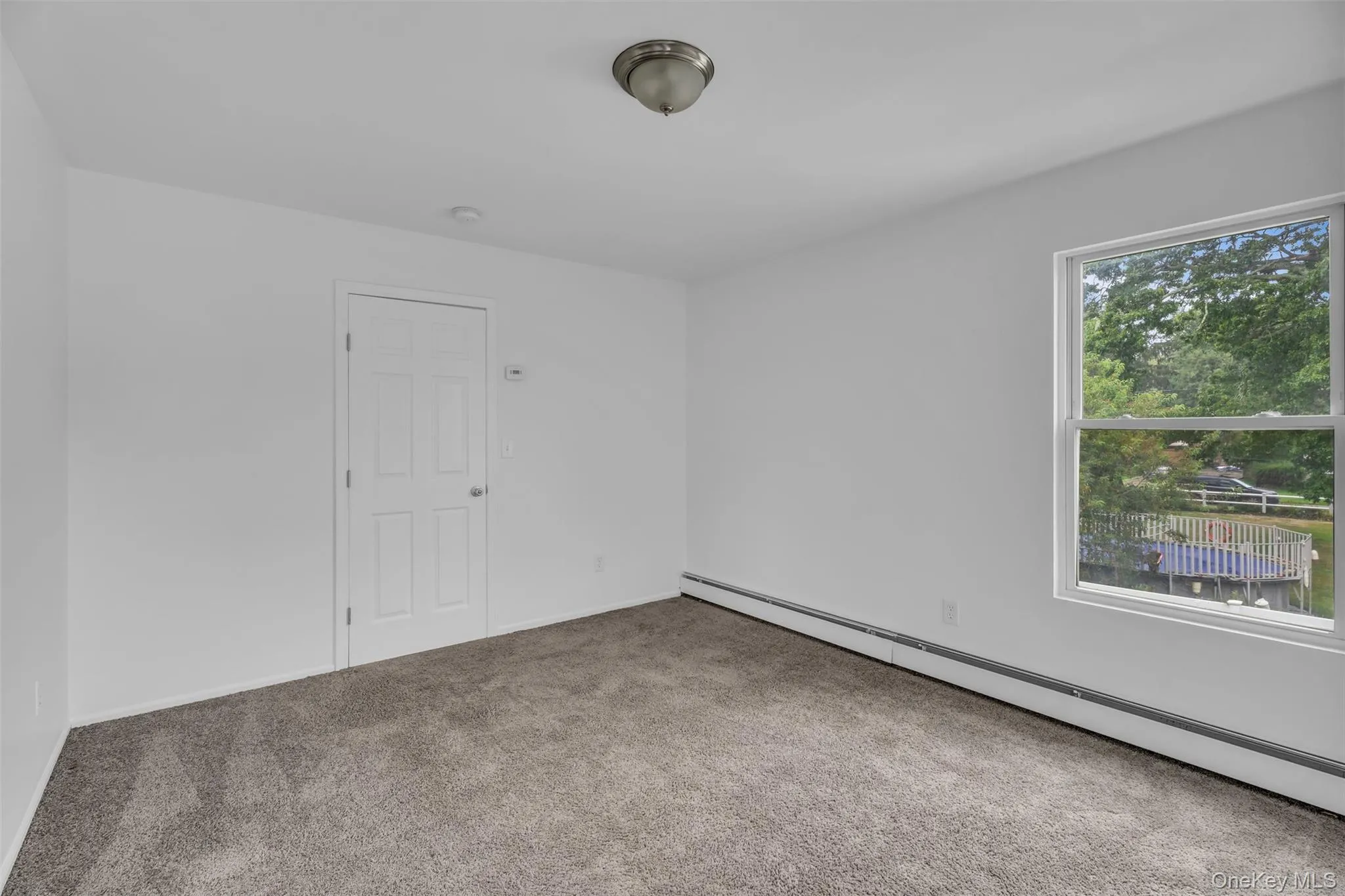 Unfurnished room featuring a baseboard heating unit and carpet floors Unfurnished room featuring a baseboard heating unit and carpet floors