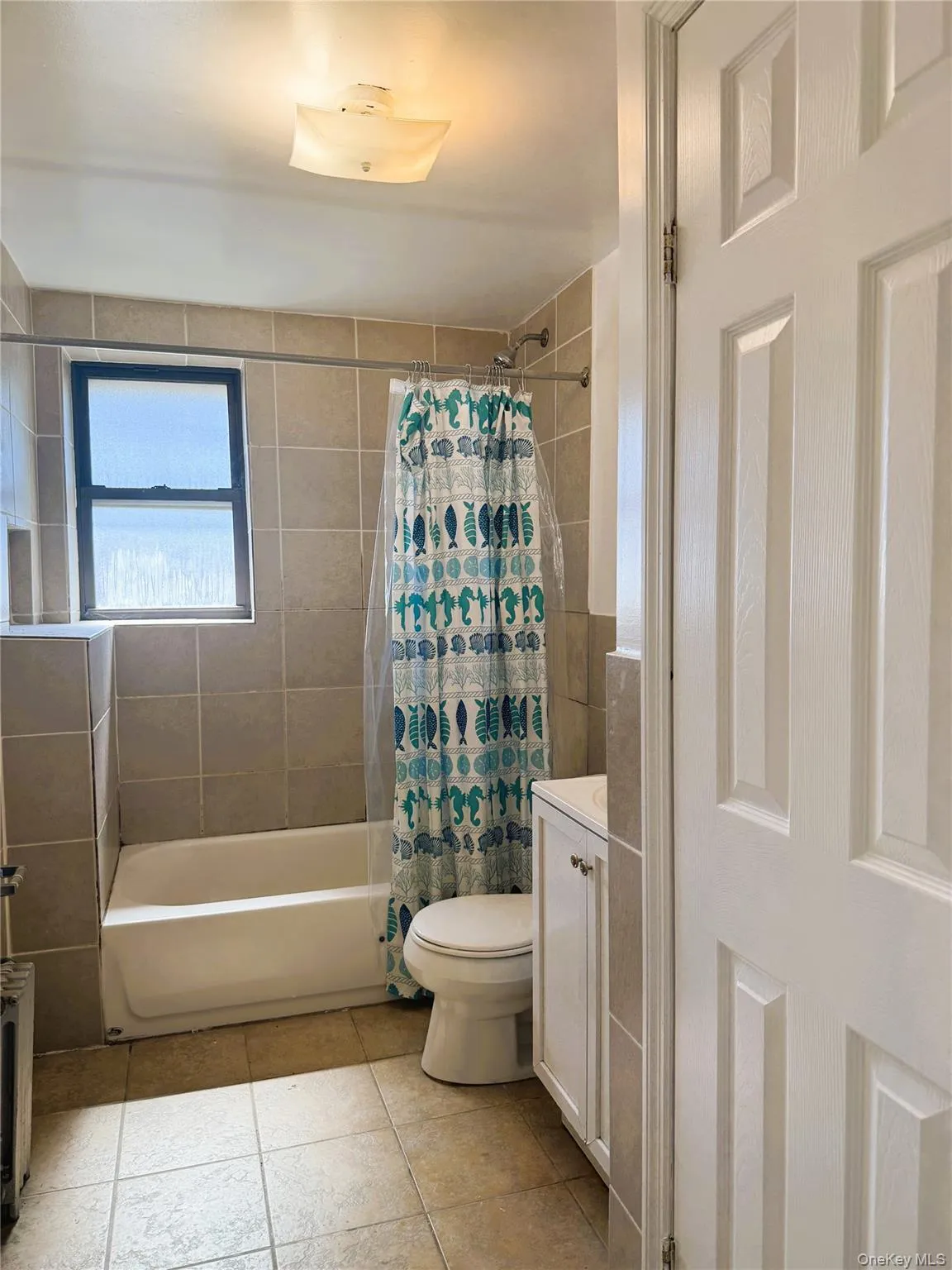 Full bath with shower / bathtub combination with curtain, vanity, light tile patterned floors, and radiator Full bath with shower / bathtub combination with curtain, vanity, light tile patterned floors, and radiator
