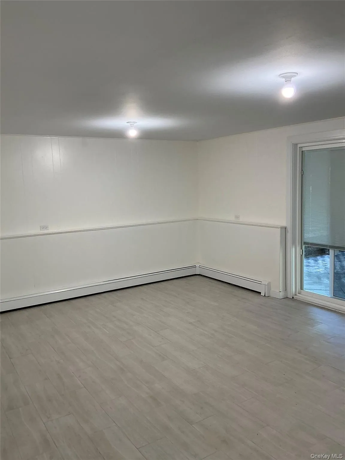 Empty room featuring light wood-style flooring and baseboard heating Empty room featuring light wood-style flooring and baseboard heating