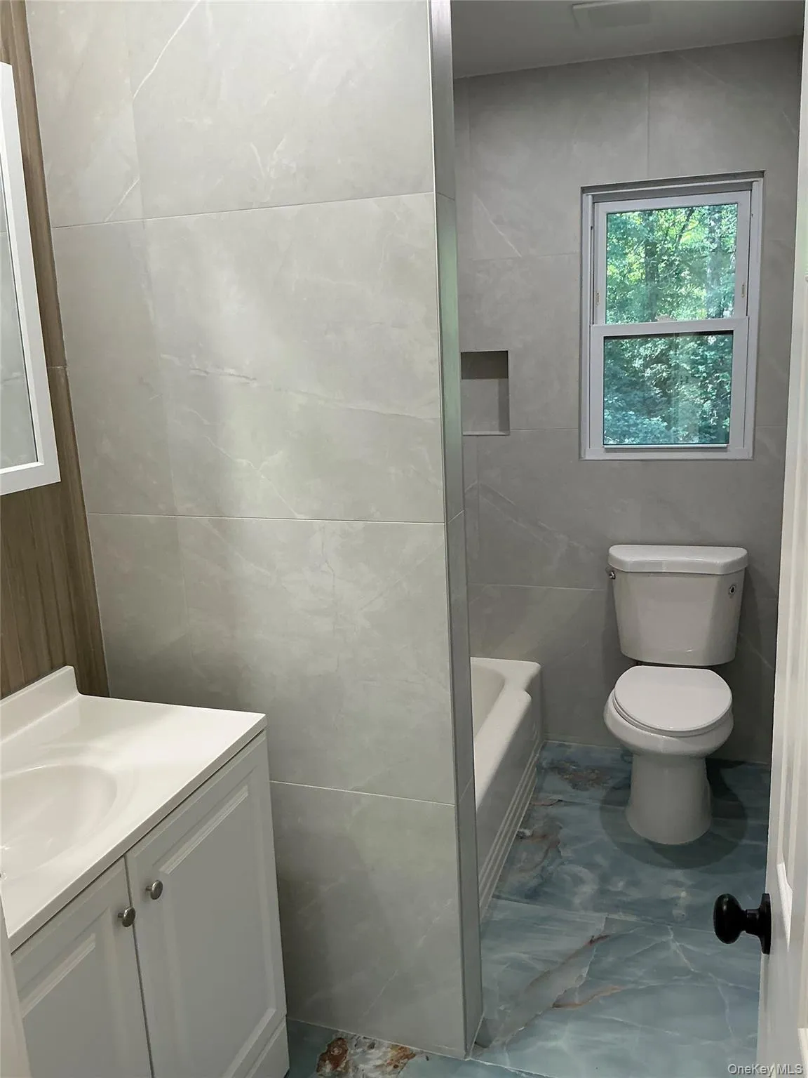 Full bath with tile walls, vanity, marble finish floors, and shower / bathtub combination Full bath with tile walls, vanity, marble finish floors, and shower / bathtub combination