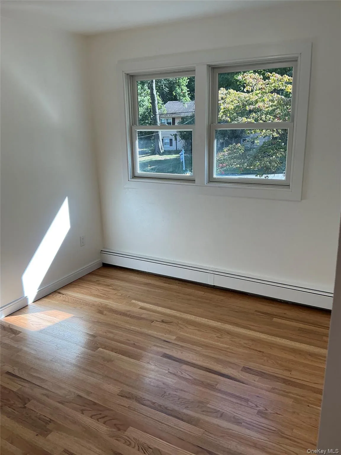 Unfurnished room featuring a baseboard radiator and light wood-style flooring Unfurnished room featuring a baseboard radiator and light wood-style flooring