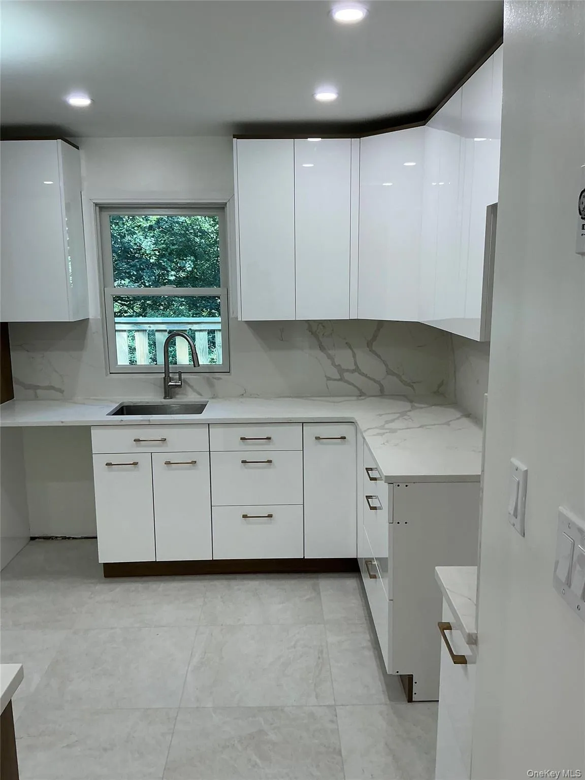 Kitchen featuring white cabinetry, modern cabinets, tasteful backsplash, recessed lighting, and light stone counters Kitchen featuring white cabinetry, modern cabinets, tasteful backsplash, recessed lighting, and light stone counters