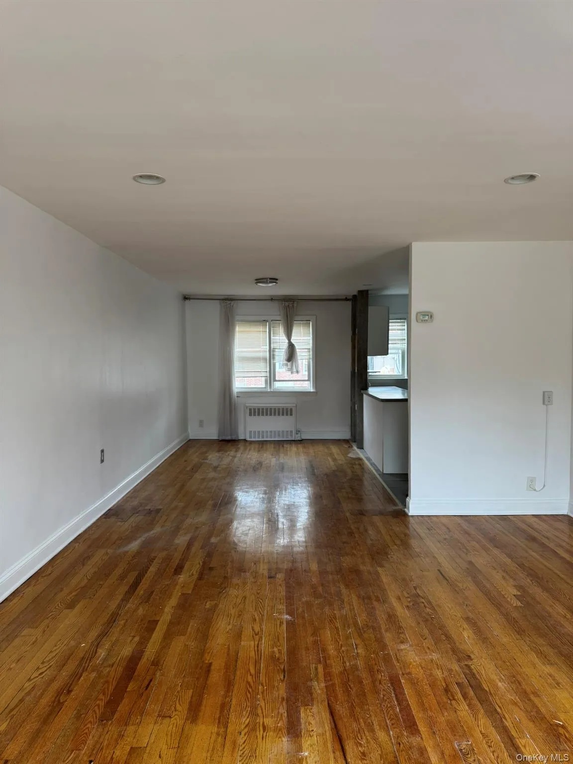 Unfurnished living room with dark wood finished floors, radiator, and recessed lighting Unfurnished living room with dark wood finished floors, radiator, and recessed lighting