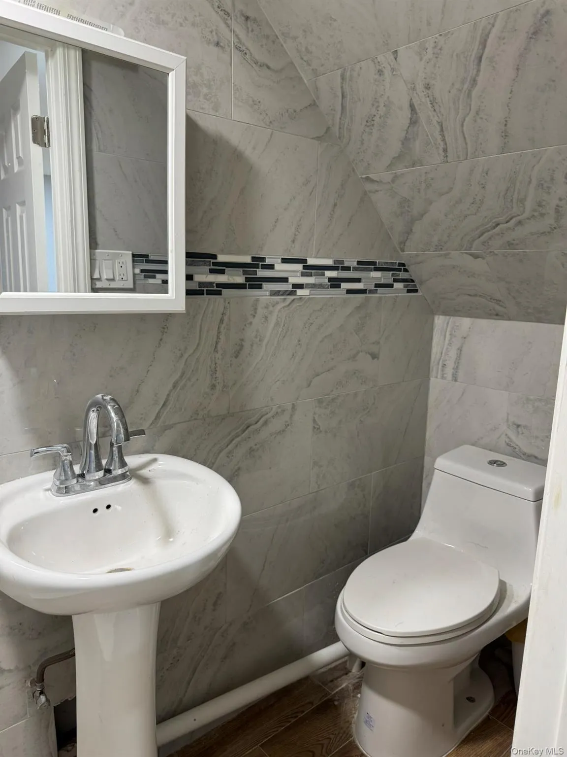 Half bath with tile walls and wood finished floors Half bath with tile walls and wood finished floors