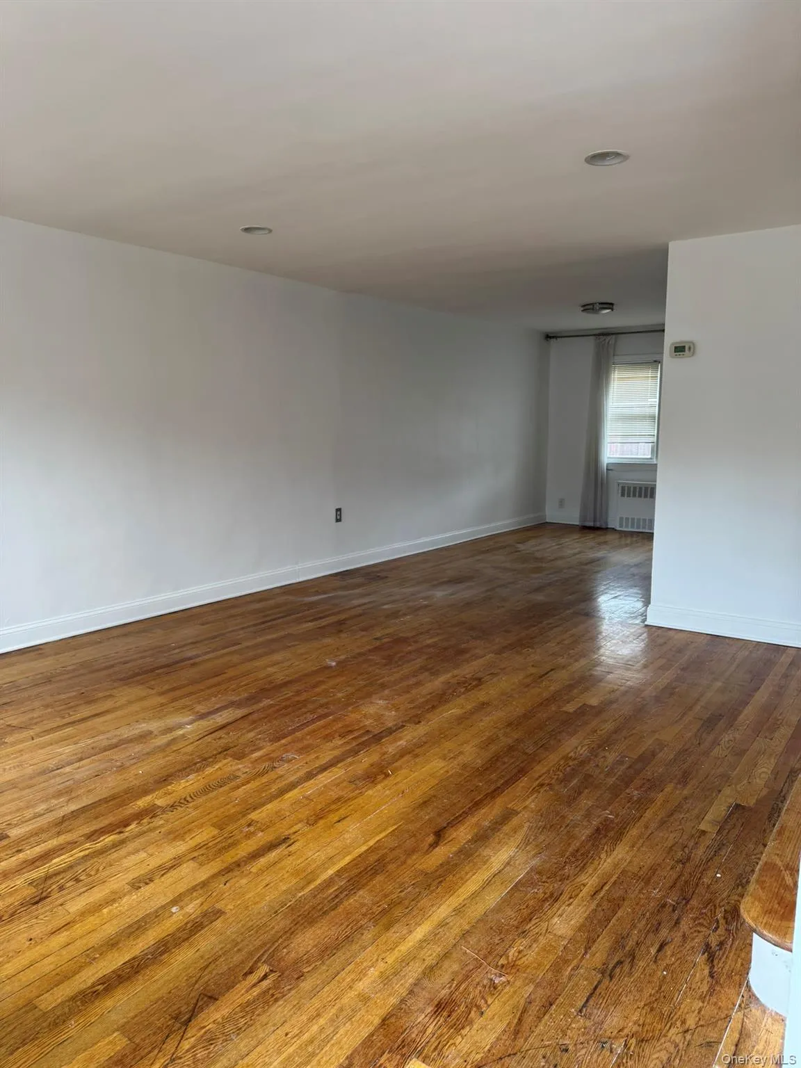 Unfurnished room featuring dark wood-style flooring and radiator Unfurnished room featuring dark wood-style flooring and radiator