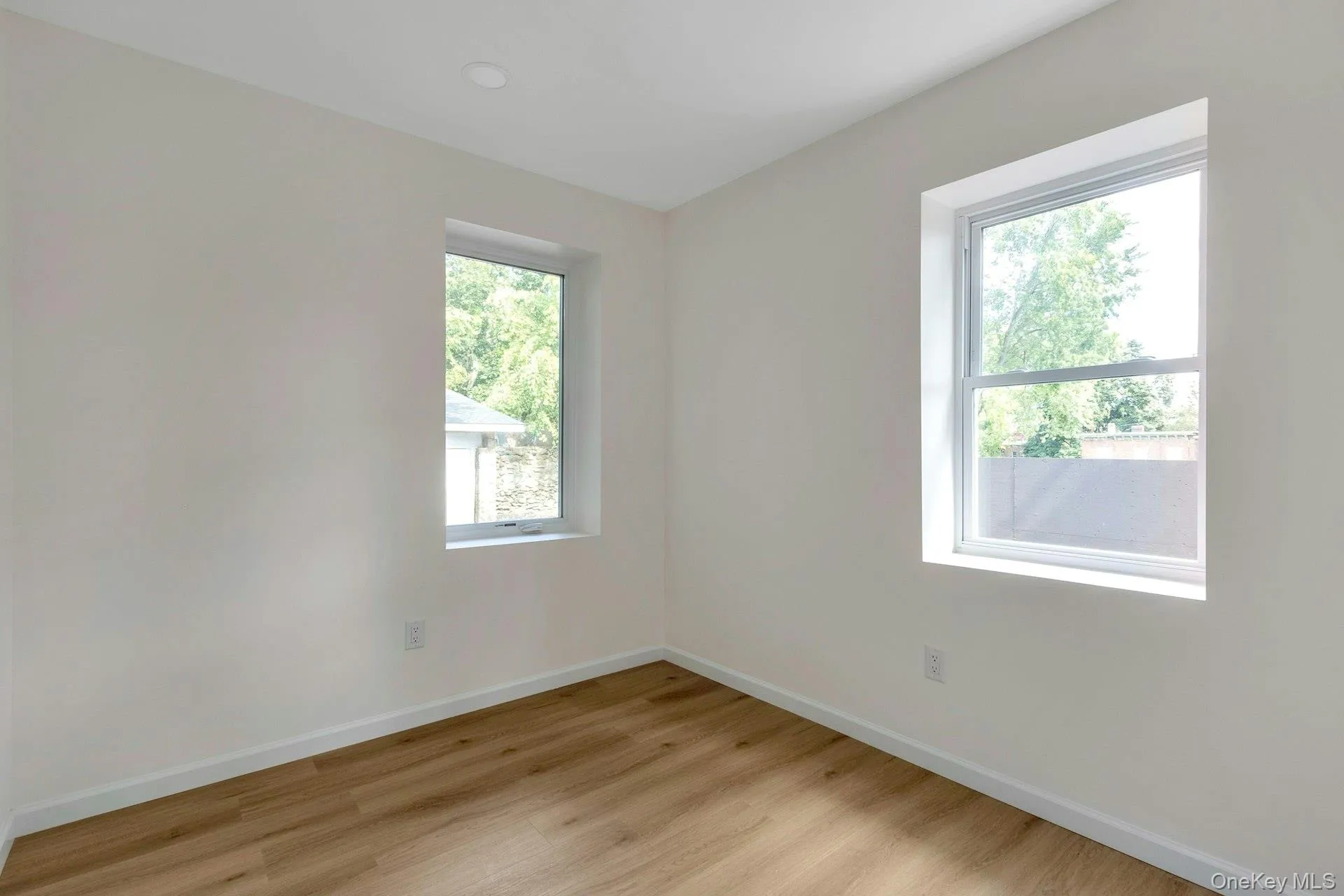 Unfurnished room with light wood finished floors and baseboards Unfurnished room with light wood finished floors and baseboards