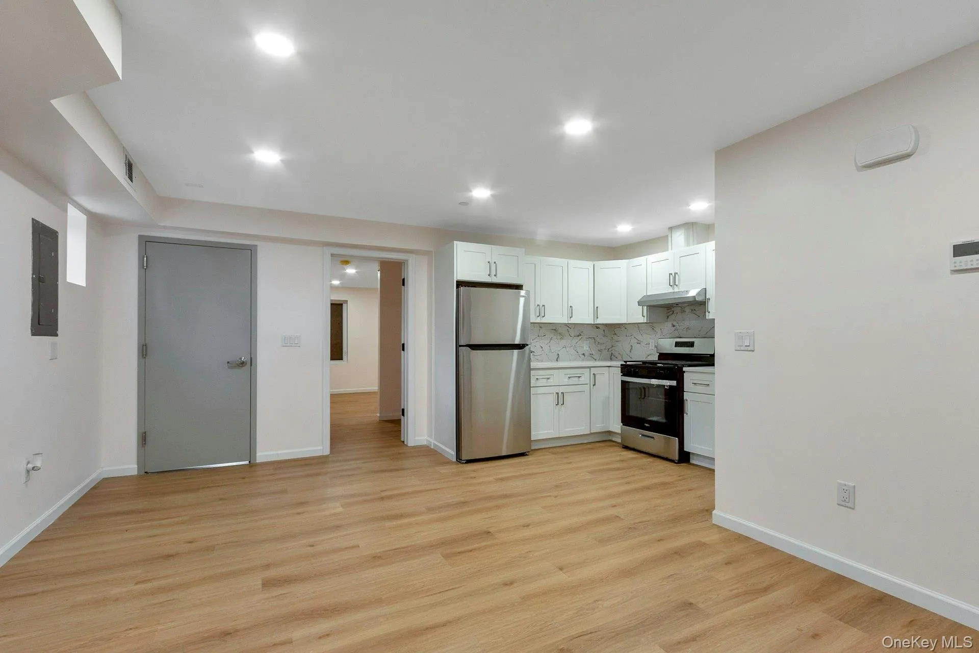 Kitchen featuring appliances with stainless steel finishes, white cabinets, tasteful backsplash, light wood-style flooring, and recessed lighting Kitchen featuring appliances with stainless steel finishes, white cabinets, tasteful backsplash, light wood-style flooring, and recessed lighting