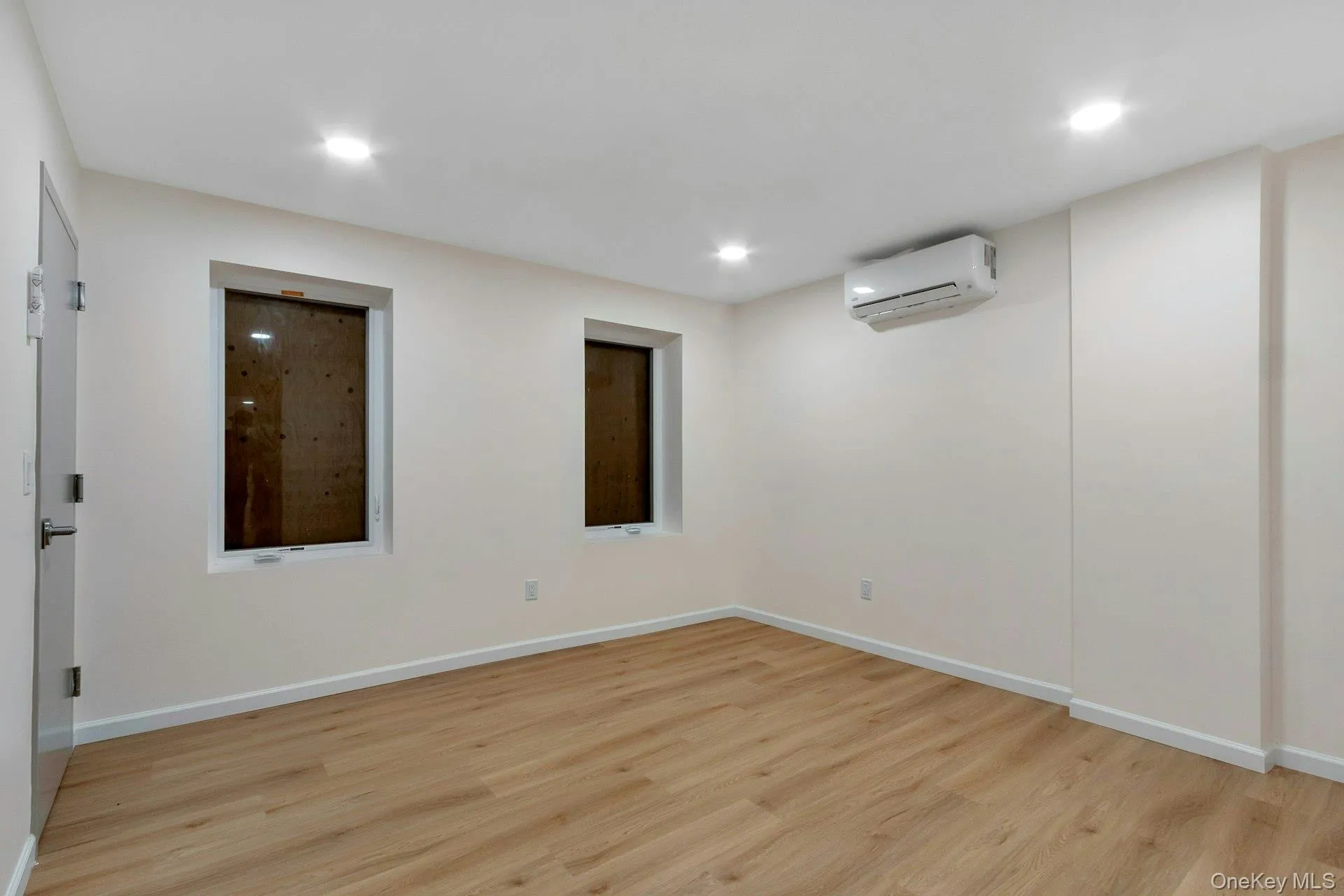 Basement with light wood-type flooring, recessed lighting, and a wall mounted AC Basement with light wood-type flooring, recessed lighting, and a wall mounted AC