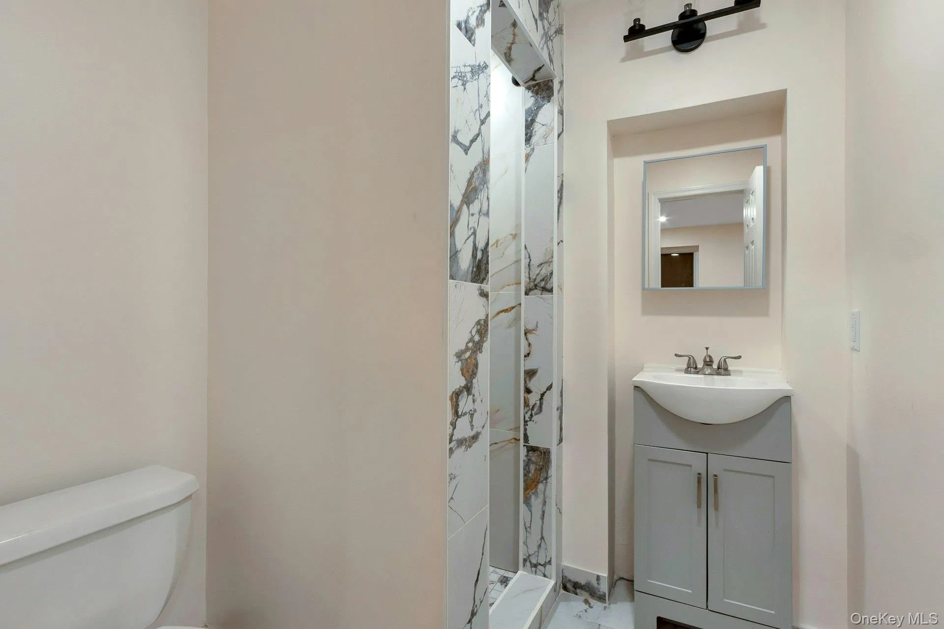 Full bathroom with vanity, a stall shower, and light marble finish flooring Full bathroom with vanity, a stall shower, and light marble finish flooring