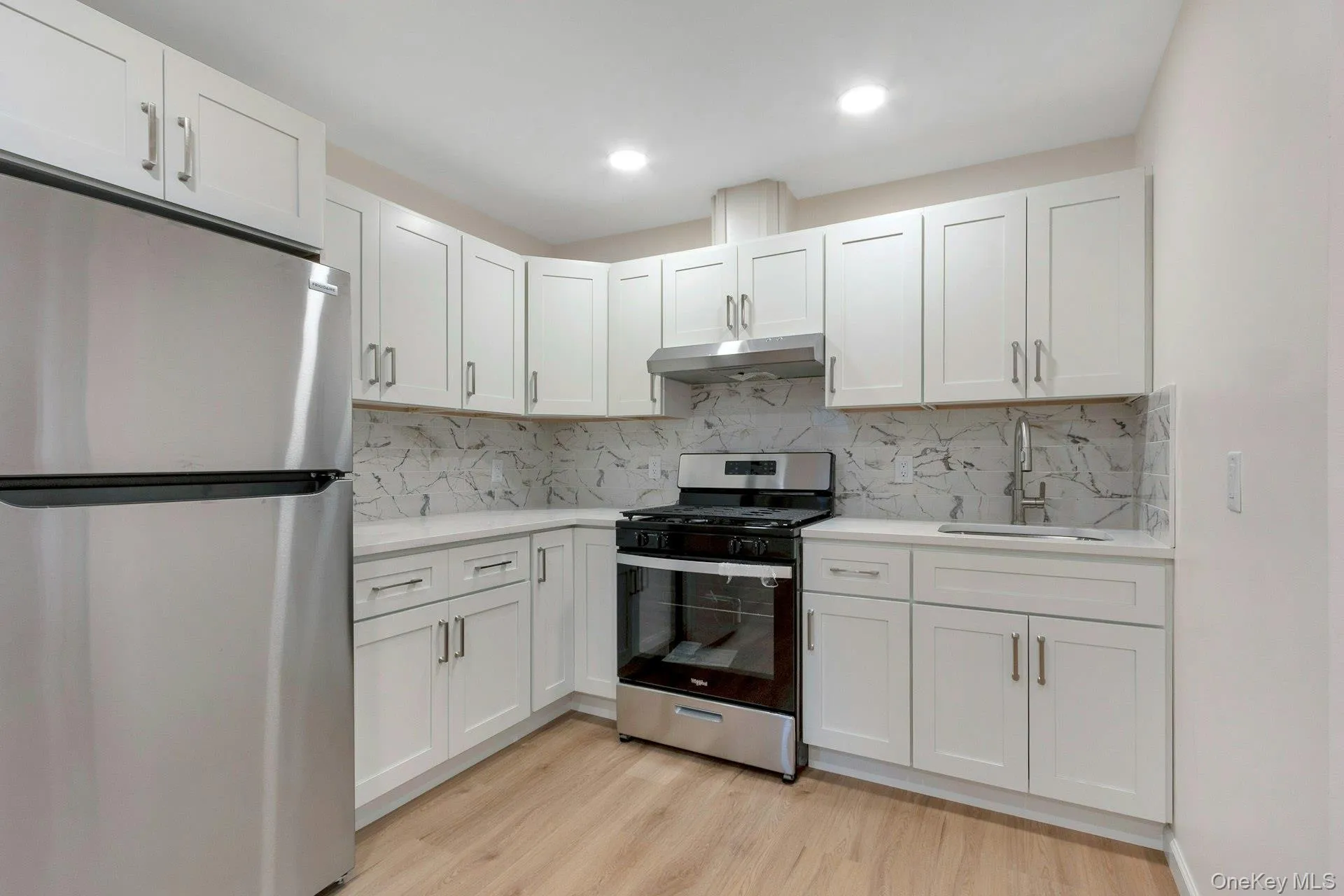 Kitchen featuring stainless steel appliances, white cabinets, light wood-type flooring, and recessed lighting Kitchen featuring stainless steel appliances, white cabinets, light wood-type flooring, and recessed lighting