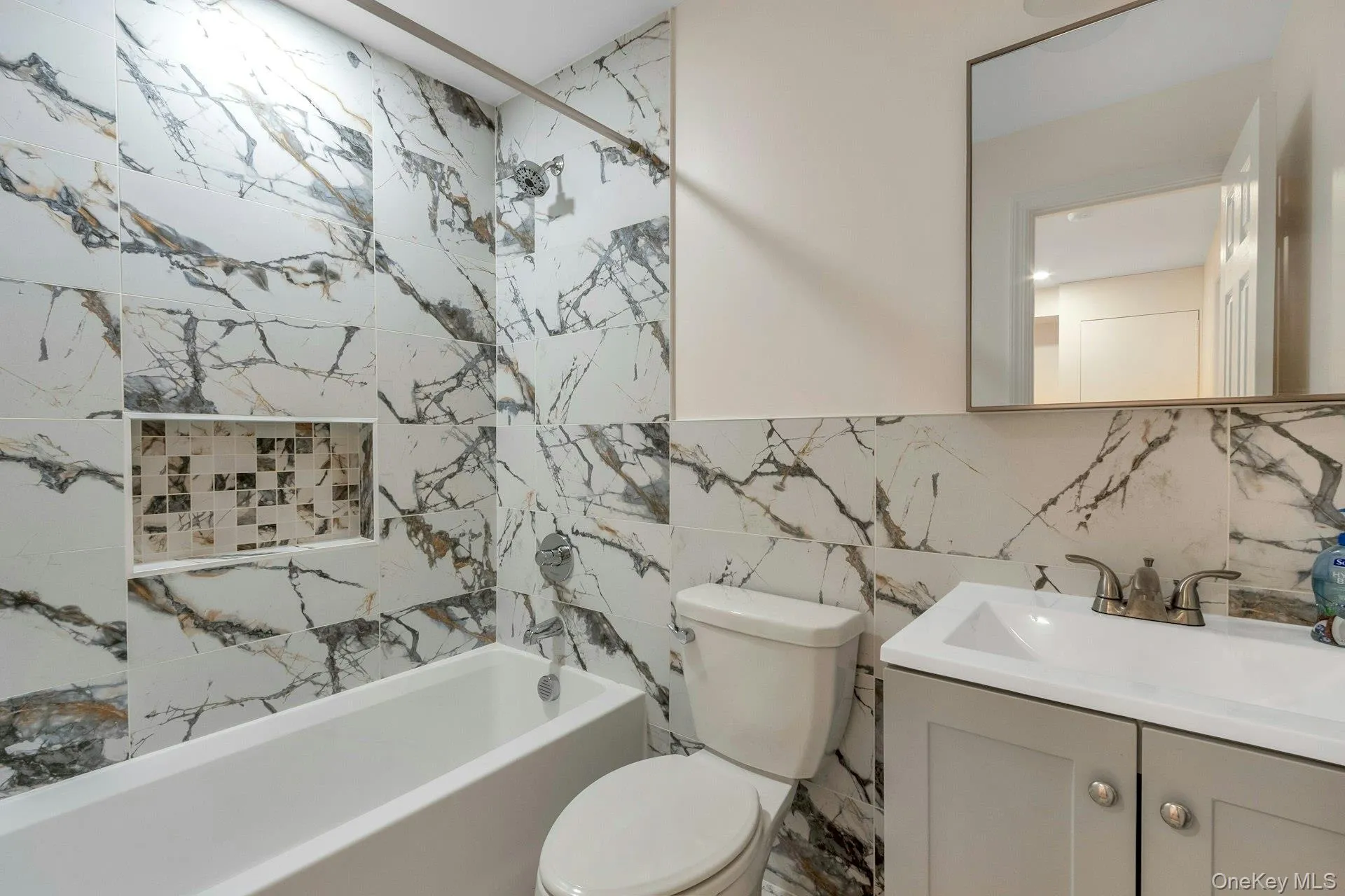 Bathroom featuring washtub / shower combination, vanity, and tile walls Bathroom featuring washtub / shower combination, vanity, and tile walls
