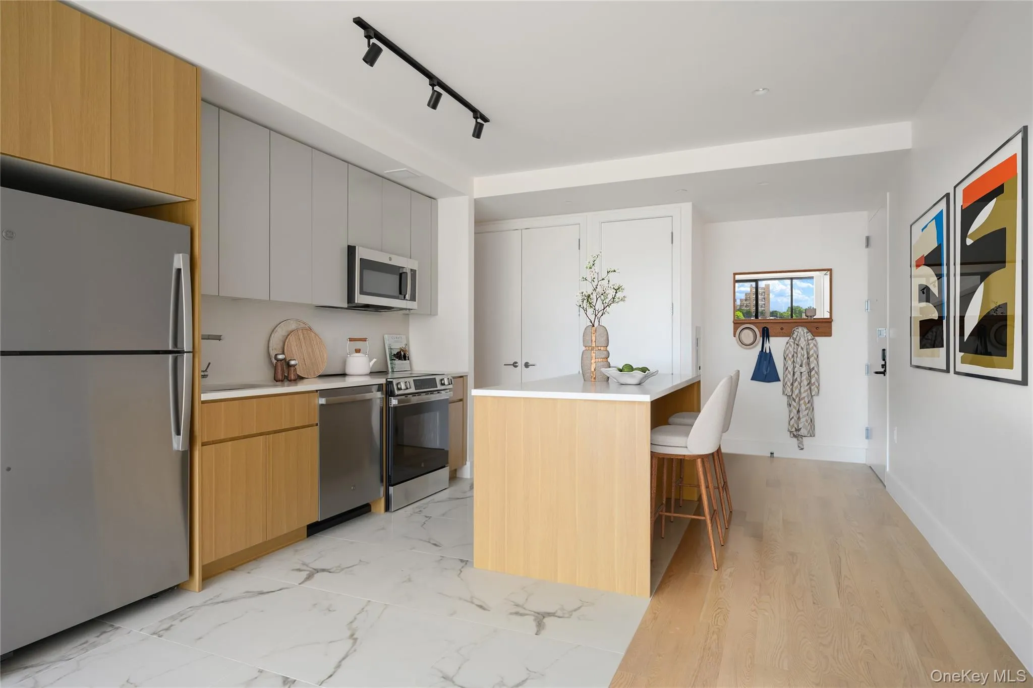 Kitchen featuring appliances with stainless steel finishes, modern cabinets, a kitchen breakfast bar, and rail lighting Kitchen featuring appliances with stainless steel finishes, modern cabinets, a kitchen breakfast bar, and rail lighting