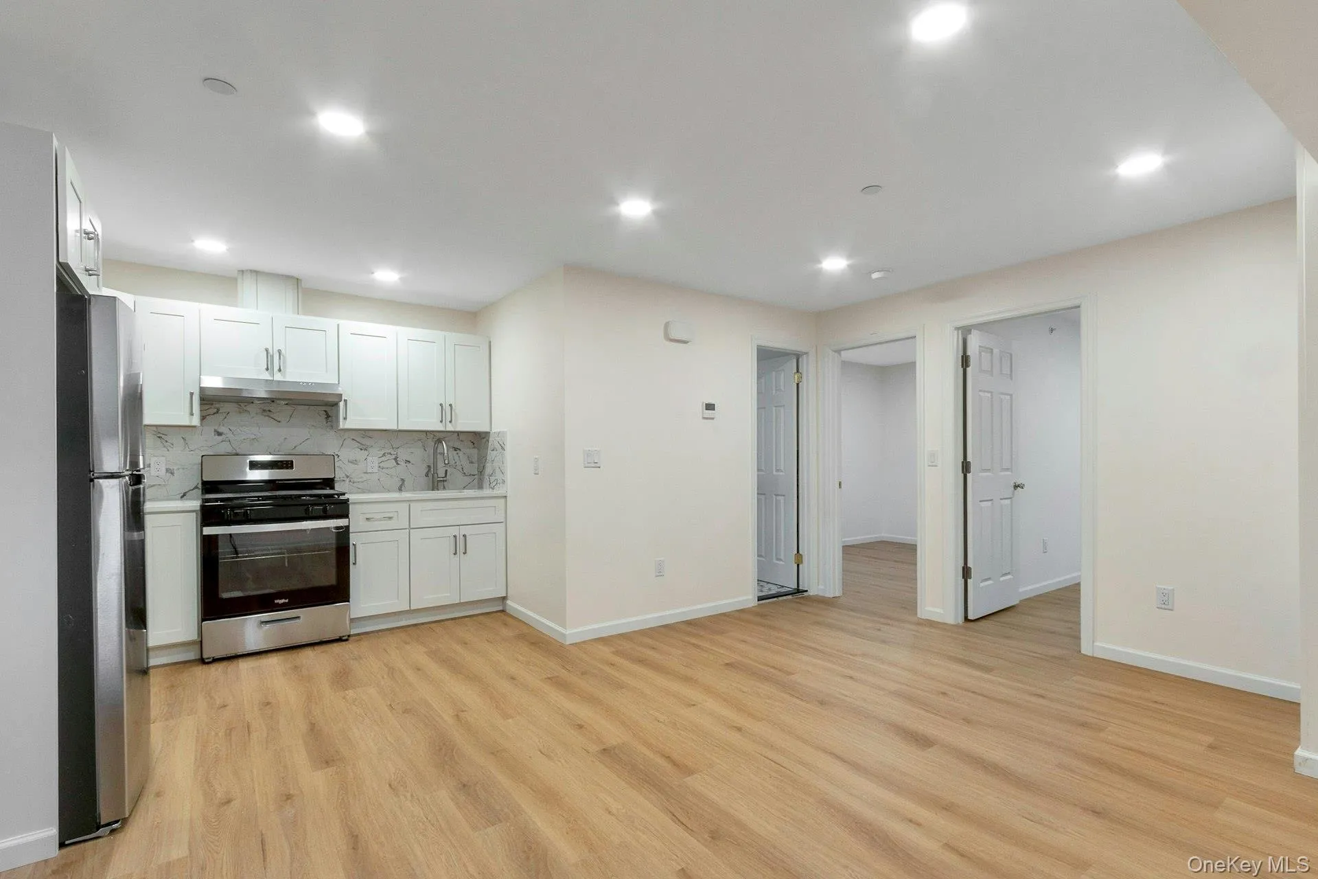 Kitchen featuring stainless steel appliances, white cabinets, backsplash, light wood-style floors, and recessed lighting Kitchen featuring stainless steel appliances, white cabinets, backsplash, light wood-style floors, and recessed lighting