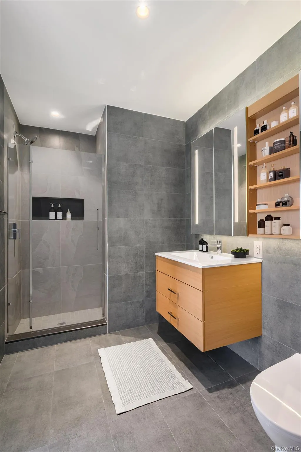 Bathroom with tile walls, vanity, a shower stall, and dark tile patterned floors Bathroom with tile walls, vanity, a shower stall, and dark tile patterned floors