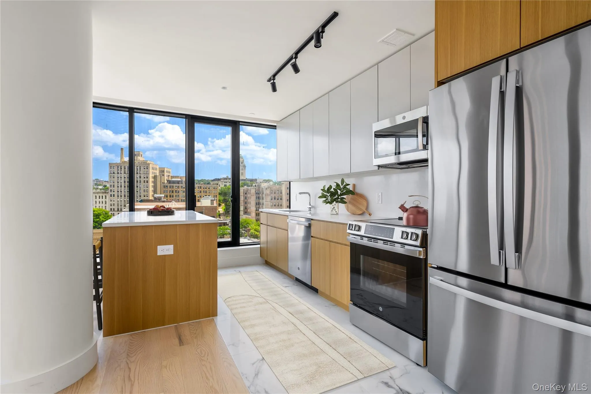 Kitchen with appliances with stainless steel finishes, modern cabinets, white cabinetry, track lighting, and brown cabinetry Kitchen with appliances with stainless steel finishes, modern cabinets, white cabinetry, track lighting, and brown cabinetry