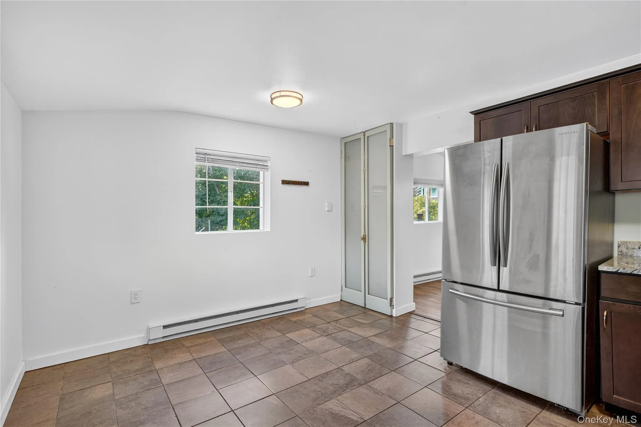 Kitchen featuring freestanding refrigerator, dark brown cabinetry, baseboard heating, and healthy amount of natural light Kitchen featuring freestanding refrigerator, dark brown cabinetry, baseboard heating, and healthy amount of natural light