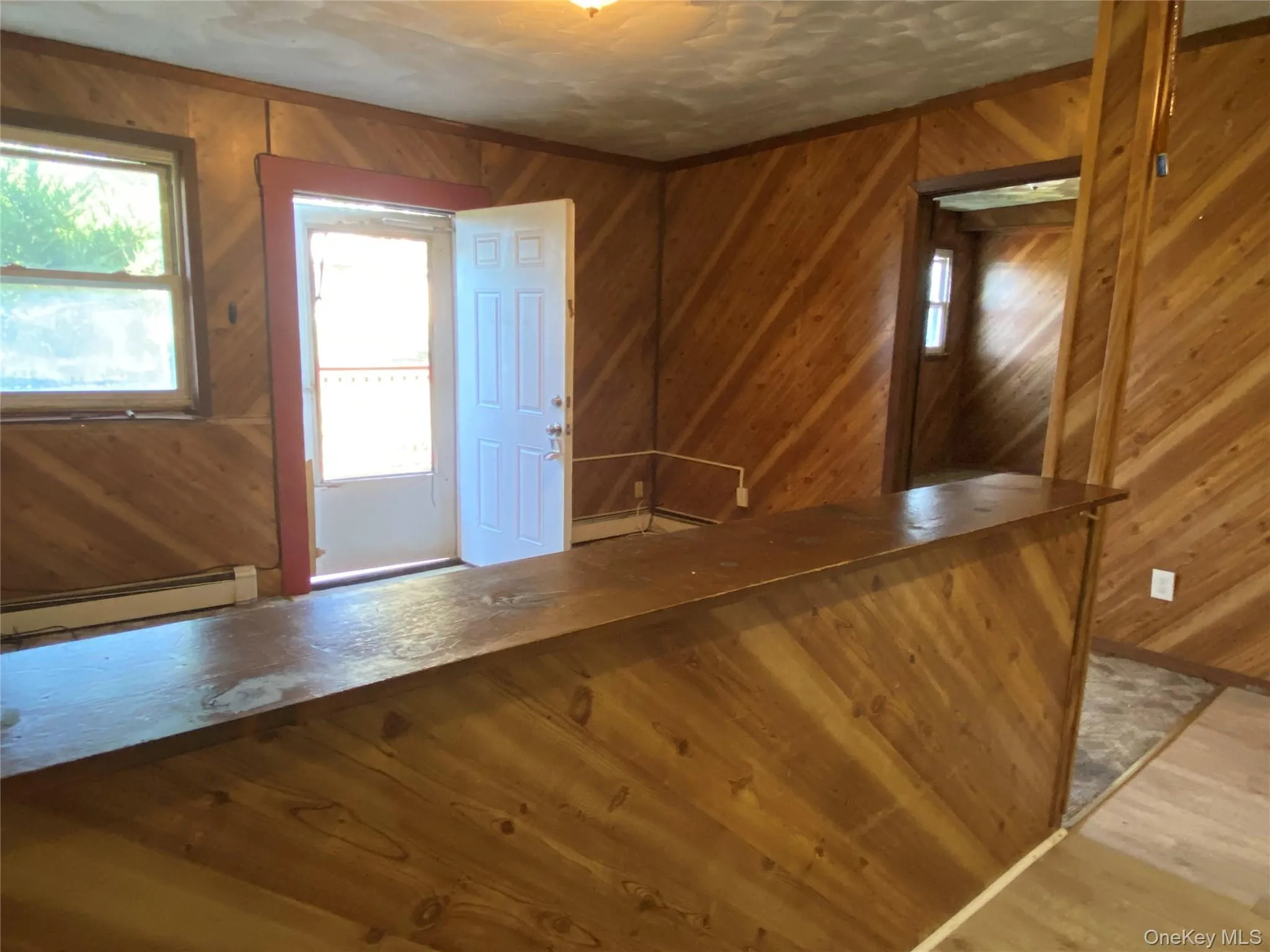 Entryway with wooden walls, a baseboard heating unit, wood finished floors, and a textured ceiling Entryway with wooden walls, a baseboard heating unit, wood finished floors, and a textured ceiling