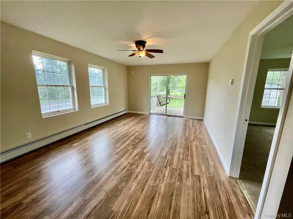 Empty room featuring a baseboard heating unit, ceiling fan, and hardwood / wood-style floors Empty room featuring a baseboard heating unit, ceiling fan, and hardwood / wood-style floors