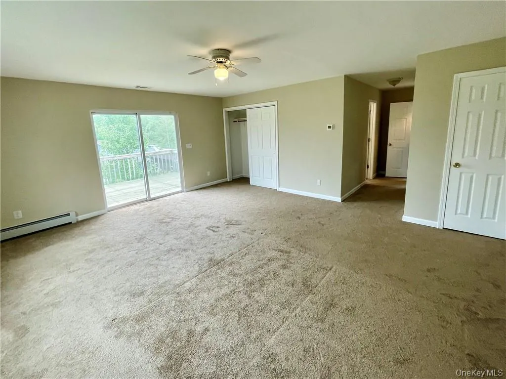 Unfurnished bedroom with a baseboard heating unit, access to outside, a closet, ceiling fan, and carpet flooring Unfurnished bedroom with a baseboard heating unit, access to outside, a closet, ceiling fan, and carpet flooring