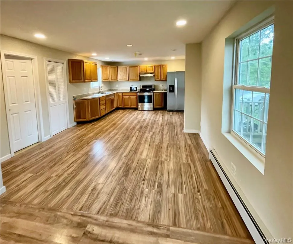 Kitchen with appliances with stainless steel finishes, light hardwood / wood-style flooring, and a baseboard radiator Kitchen with appliances with stainless steel finishes, light hardwood / wood-style flooring, and a baseboard radiator