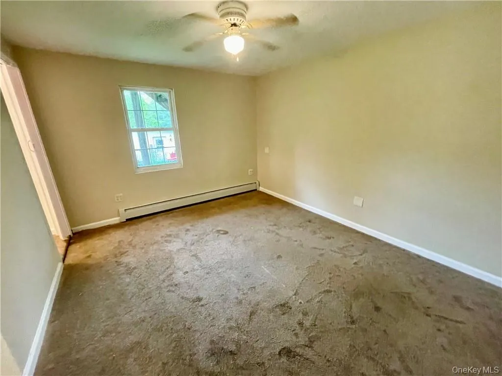 Spare room featuring ceiling fan, a baseboard radiator, and carpet Spare room featuring ceiling fan, a baseboard radiator, and carpet