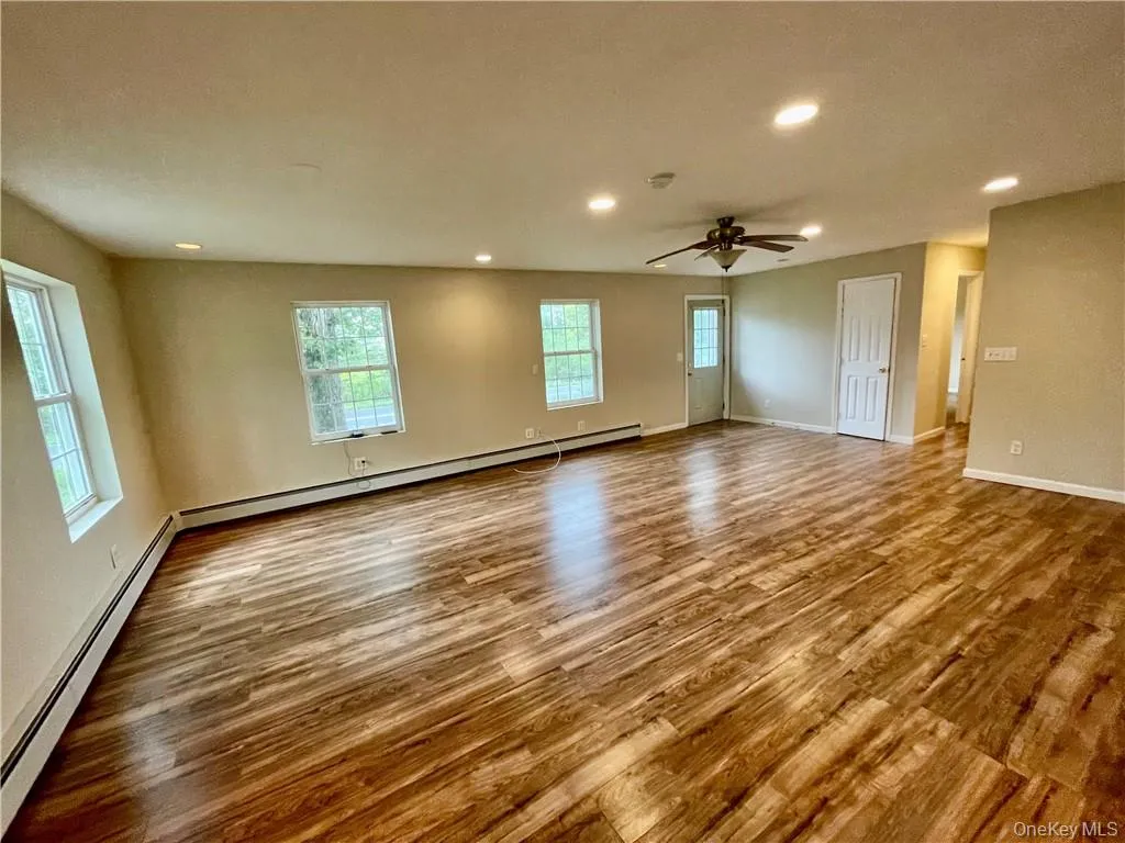 Empty room with ceiling fan, hardwood / wood-style flooring, and plenty of natural light Empty room with ceiling fan, hardwood / wood-style flooring, and plenty of natural light