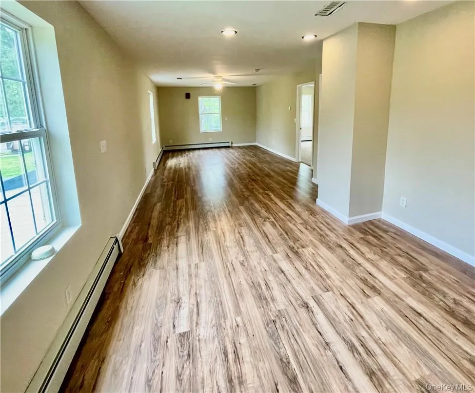 Unfurnished room with light hardwood / wood-style flooring, a wealth of natural light, and baseboard heating Unfurnished room with light hardwood / wood-style flooring, a wealth of natural light, and baseboard heating