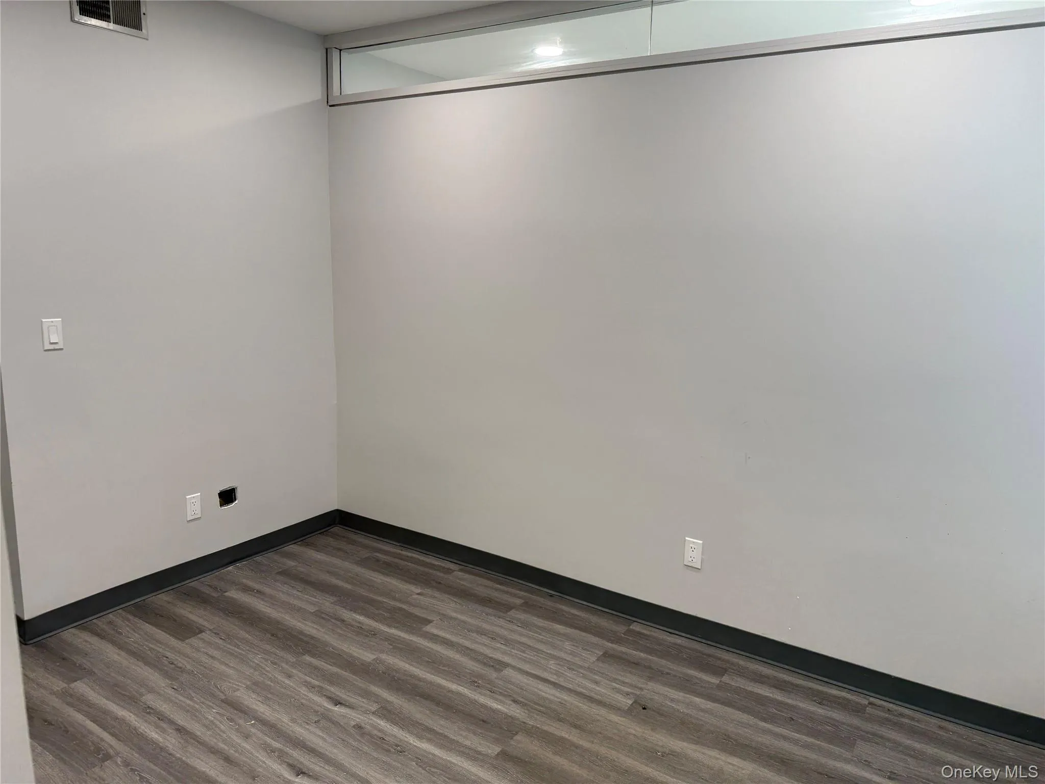 Unfurnished room with dark wood-style flooring and baseboards Unfurnished room with dark wood-style flooring and baseboards