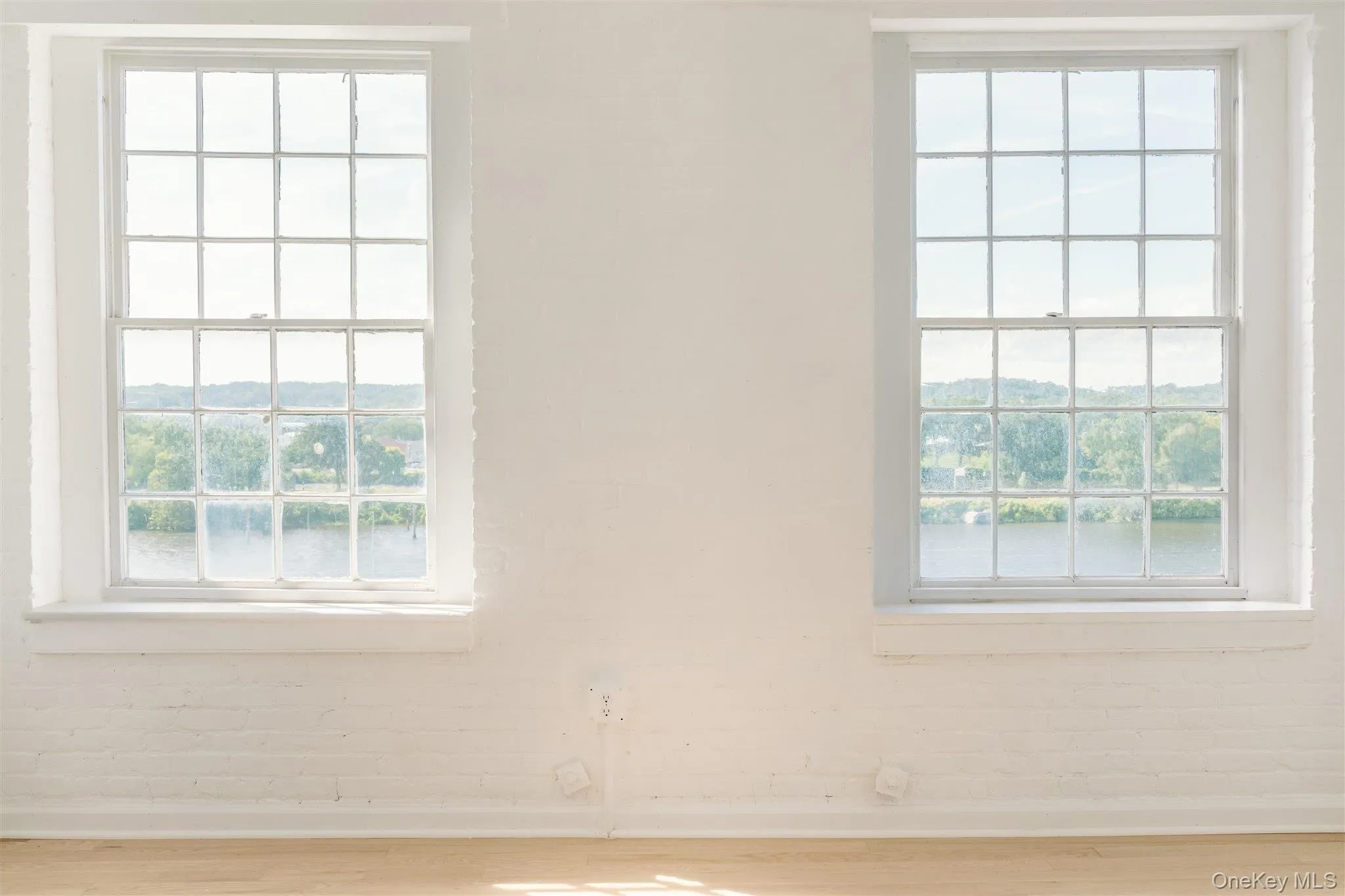 Unfurnished room with plenty of natural light, wood finished floors, and a water view Unfurnished room with plenty of natural light, wood finished floors, and a water view