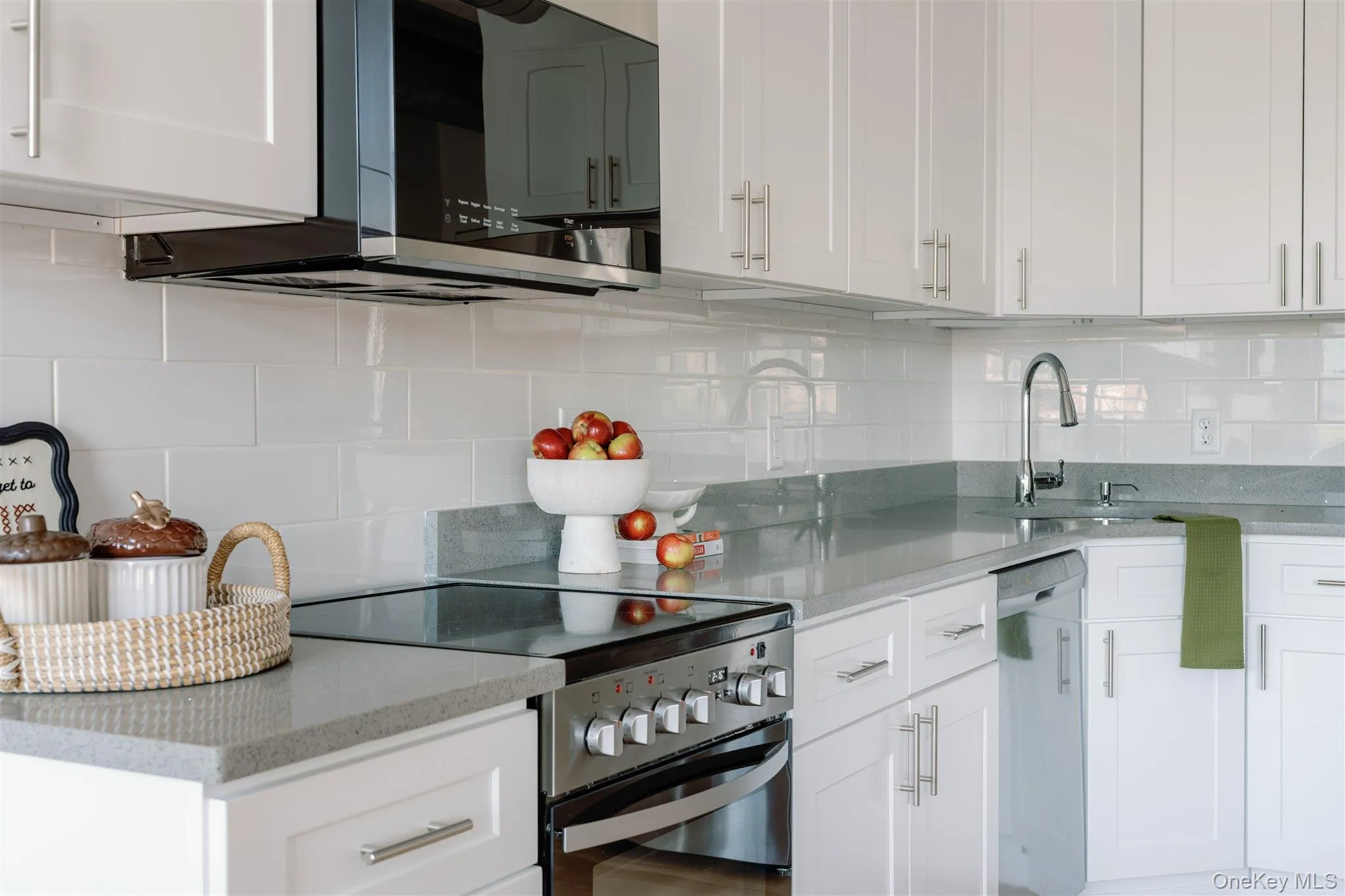 Kitchen featuring appliances with stainless steel finishes, backsplash, light stone counters, and white cabinets Kitchen featuring appliances with stainless steel finishes, backsplash, light stone counters, and white cabinets