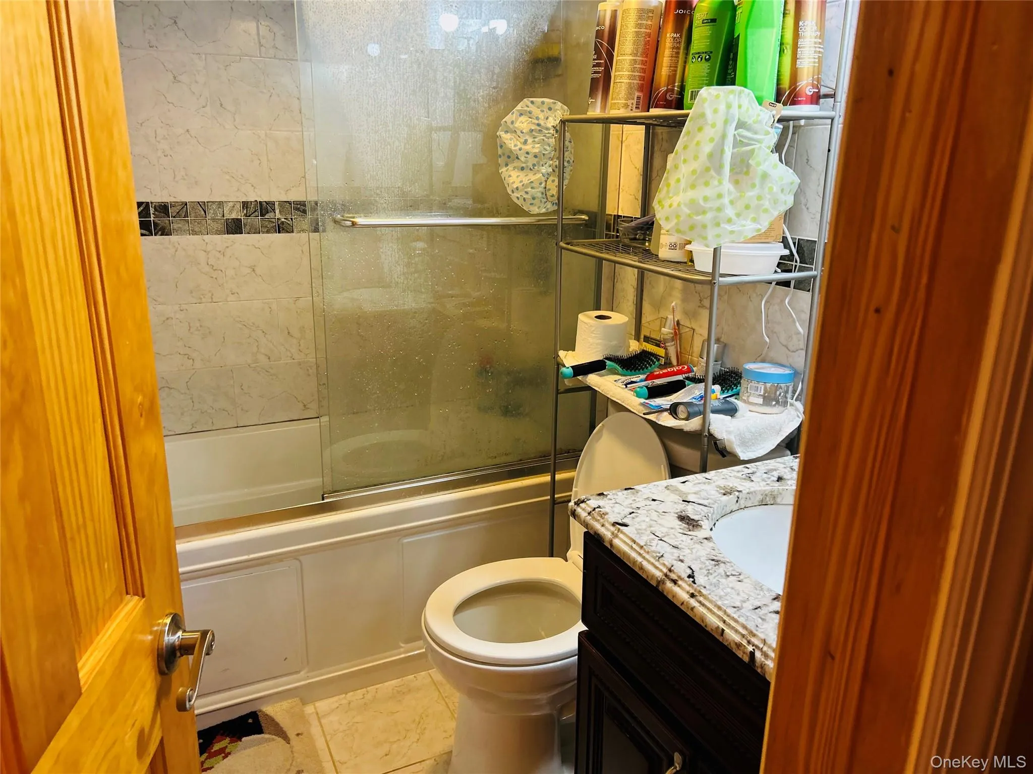 Bathroom featuring vanity, enclosed tub / shower combo, and light tile patterned floors Bathroom featuring vanity, enclosed tub / shower combo, and light tile patterned floors